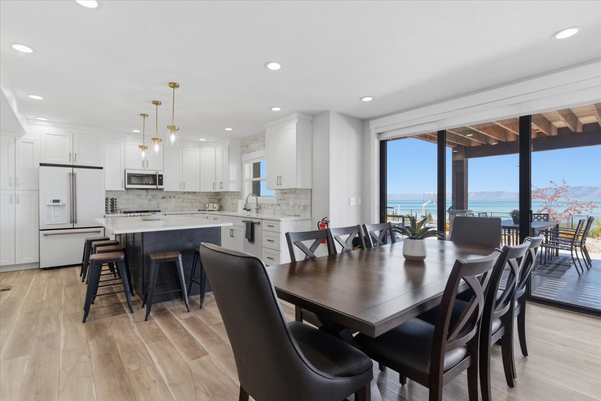Open-concept kitchen and dining area featuring light wood-finish flooring, white cabinetry, a dark-toned kitchen island with bar seating, and recessed lighting