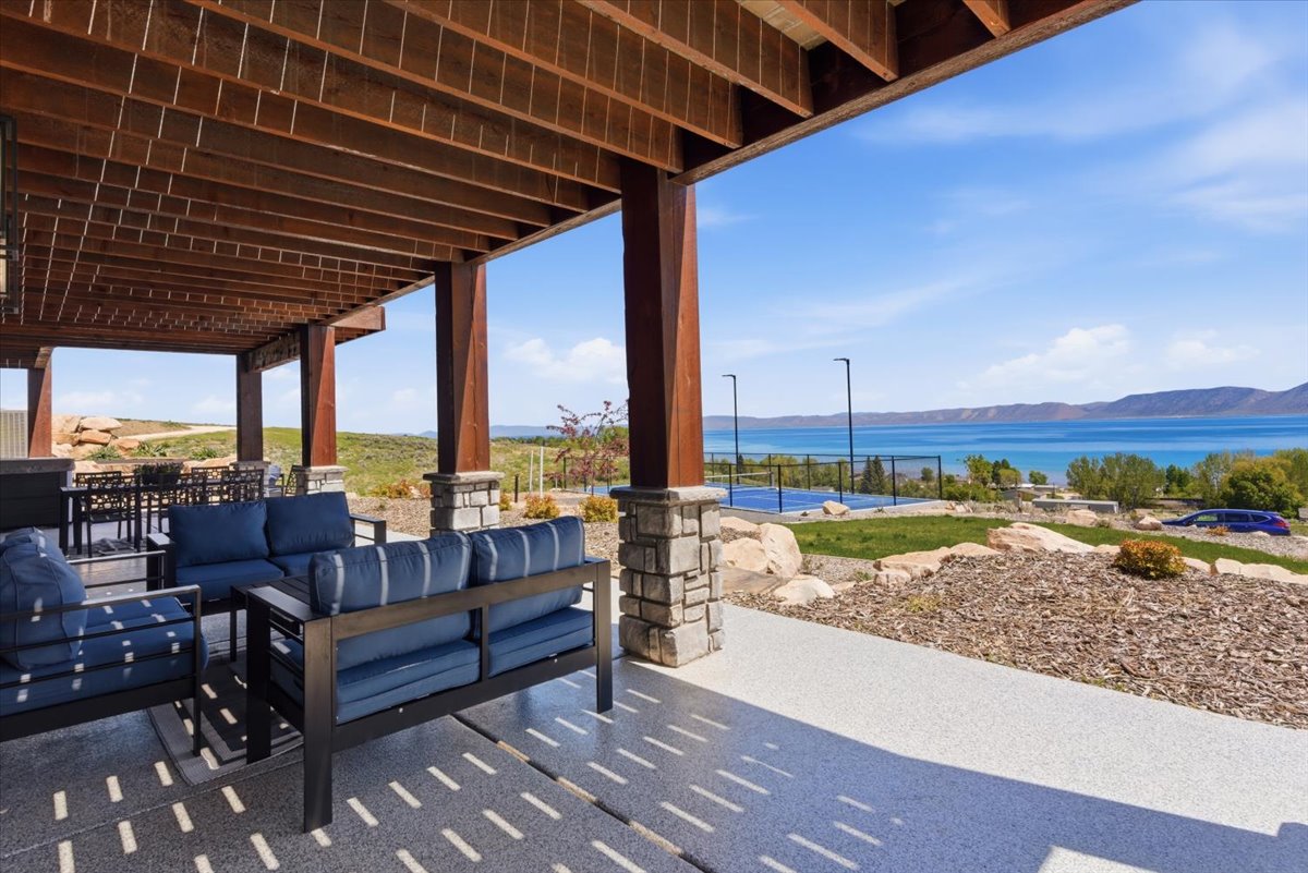 Expansive covered patio with exposed wood beam ceiling and stone-clad columns