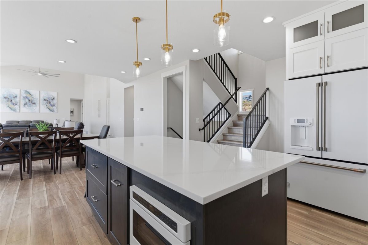 Spacious open-concept kitchen featuring a large island with a light-toned countertop, dark cabinetry, and an integrated appliance