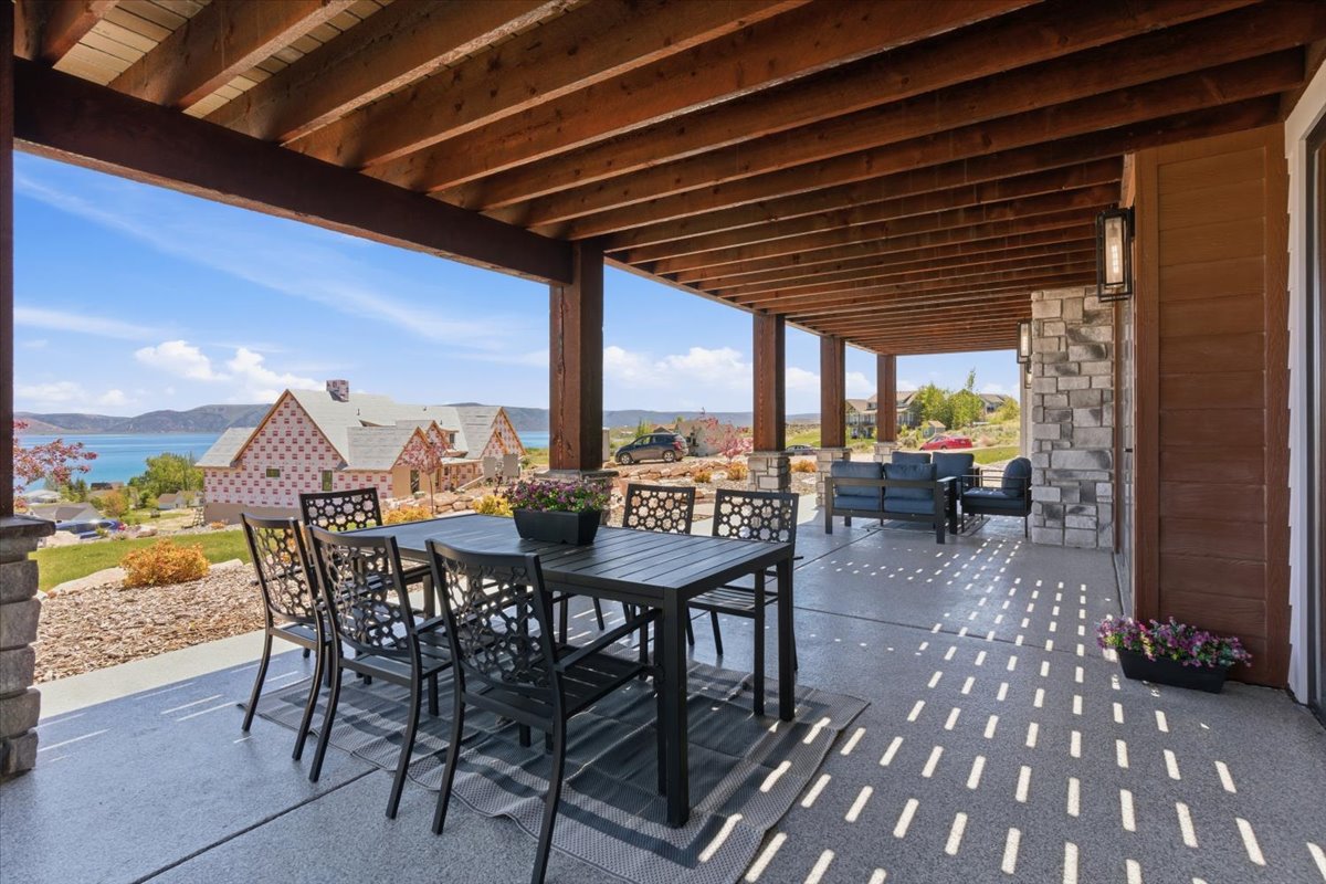 Expansive covered patio featuring a wood beam ceiling and stone column accents
