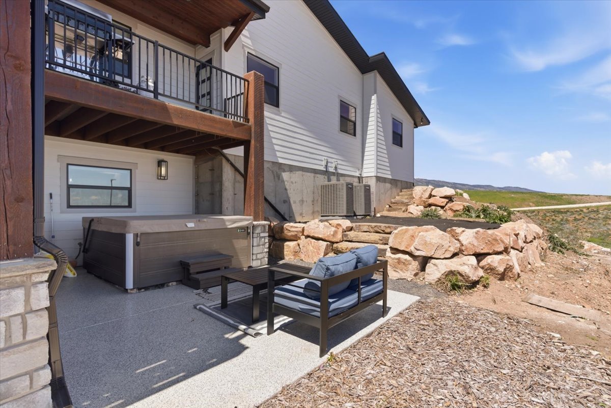 Outdoor patio featuring a hot tub, ground-level window, and a stone retaining wall