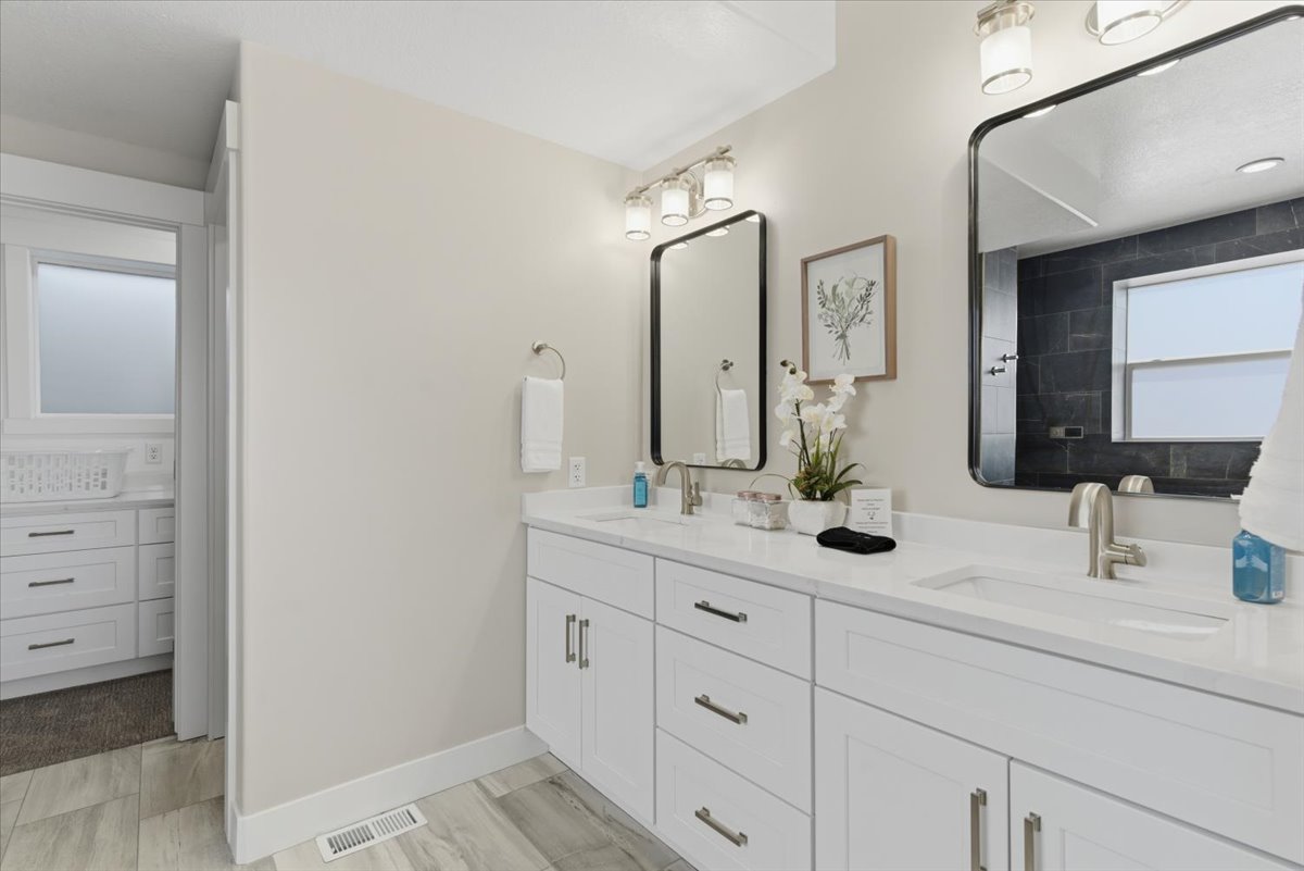 Double vanity featuring white cabinetry, integrated sinks, and brushed nickel hardware