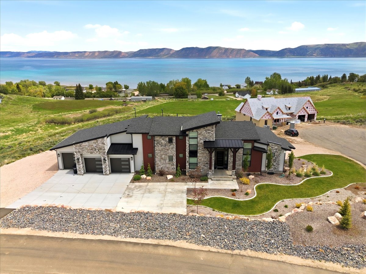 Contemporary residence featuring stone accents, a multi-car garage, and a landscaped front yard with a concrete driveway