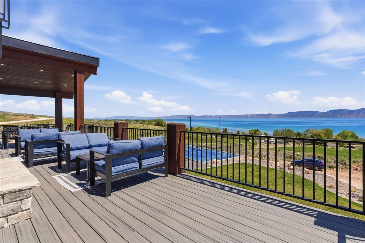 Spacious outdoor deck featuring composite decking, a black metal railing, and a stone-clad half-wall