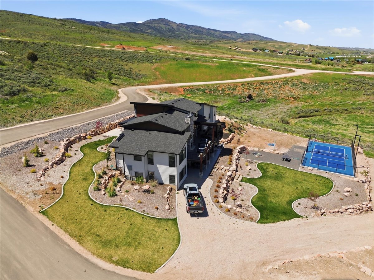 Contemporary architecture with a multi-level roofline, extensive decking, and a dedicated sports court
