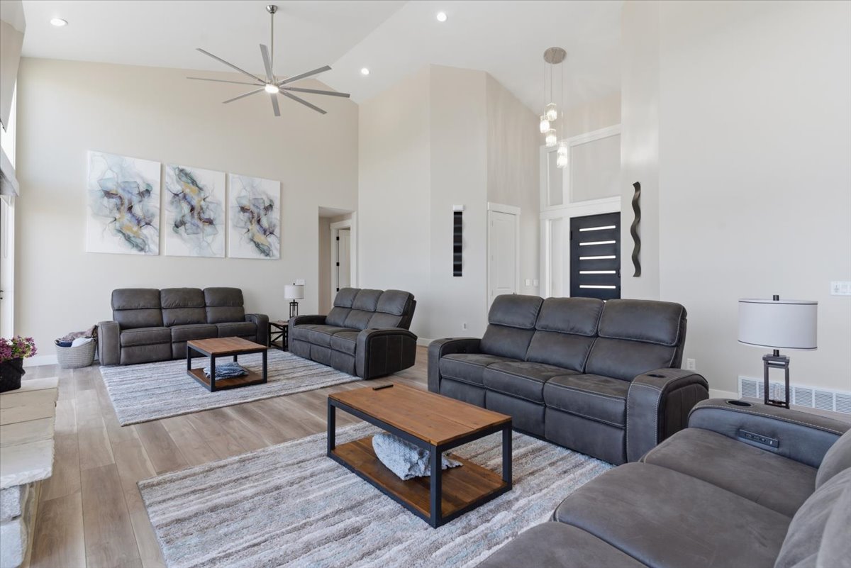 Spacious living area featuring high vaulted ceilings, light wood-finish flooring, recessed lighting, and a modern ceiling fan with integrated lighting