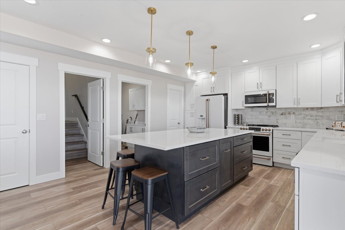 Contemporary kitchen featuring a large central island with dark cabinetry and a light-colored countertop, complemented by white perimeter cabinetry