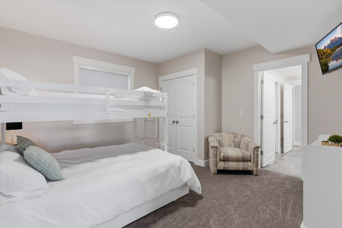 Neutral-toned interior featuring bunk beds, a wall-mounted television, and a recessed ceiling light