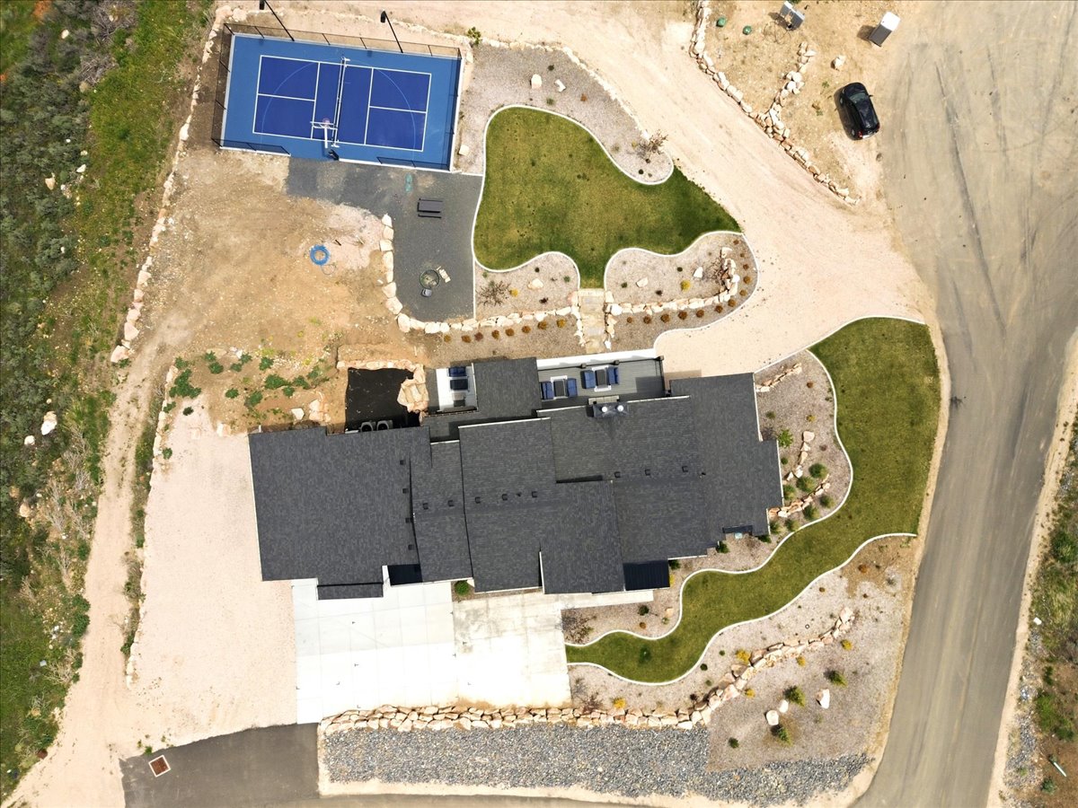 Expansive property featuring a private sports court, multiple landscaped lawn areas, and a gravel driveway