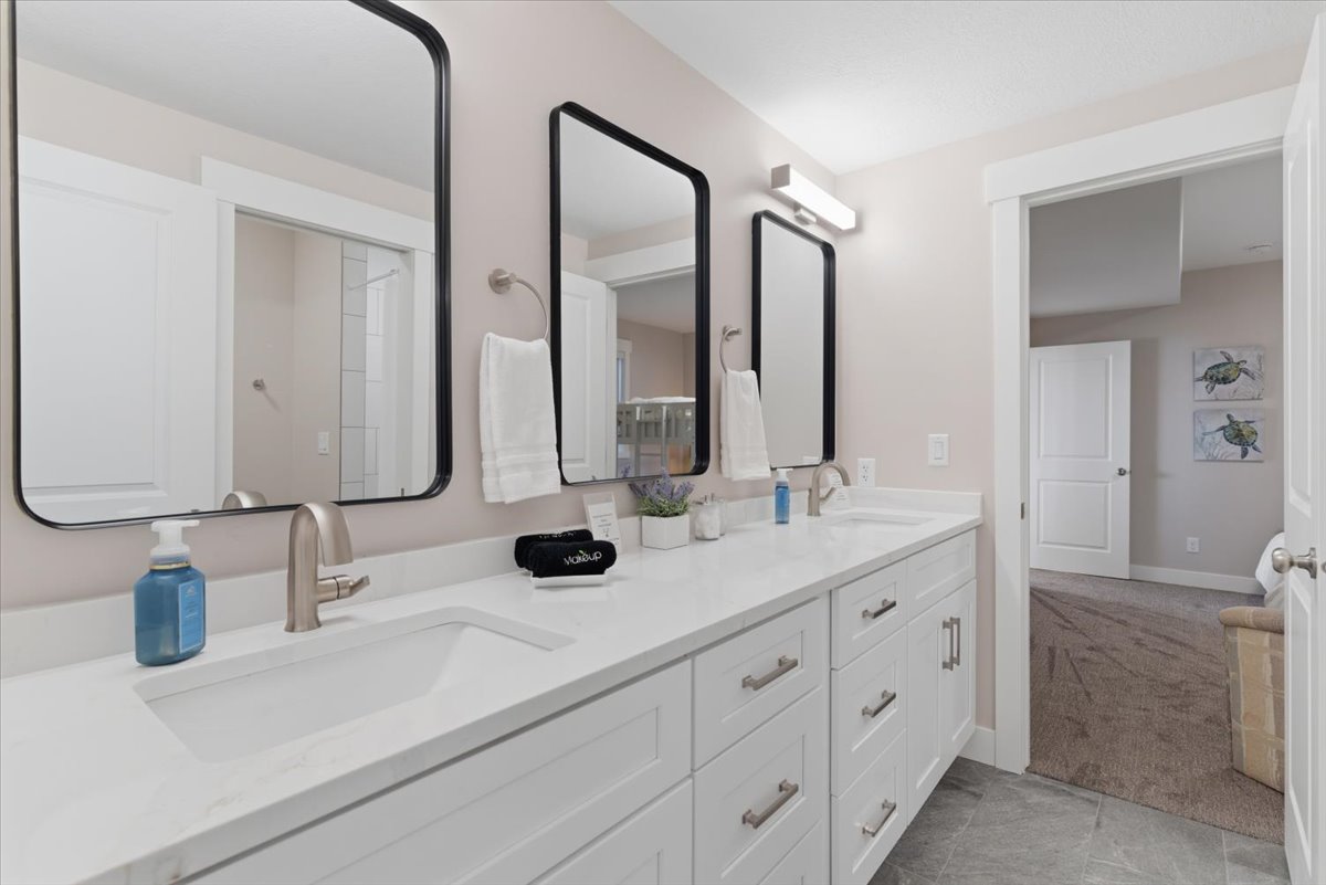 Double vanity featuring integrated sinks, white cabinetry with brushed nickel hardware, and two framed rectangular mirrors