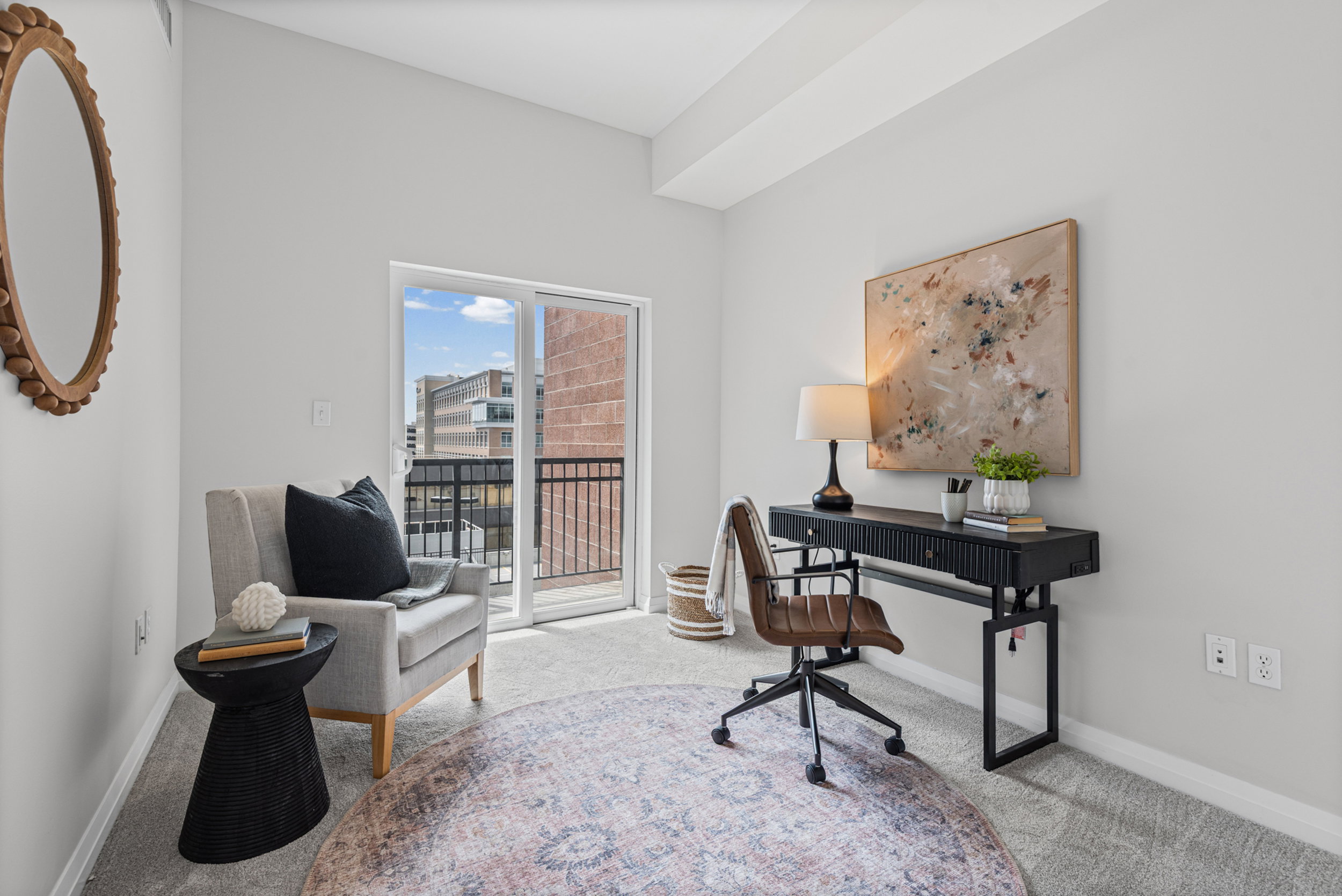 Light-filled room featuring a sliding glass door opening to a private balcony, neutral carpeting, and contemporary wall finishes