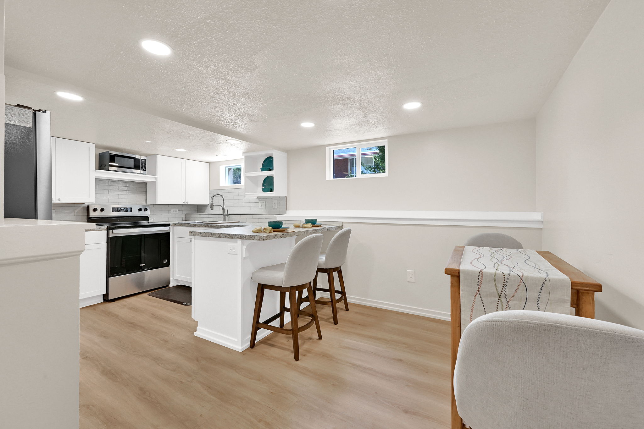 Modern kitchen featuring white cabinetry, stainless steel appliances, and wood-finish flooring