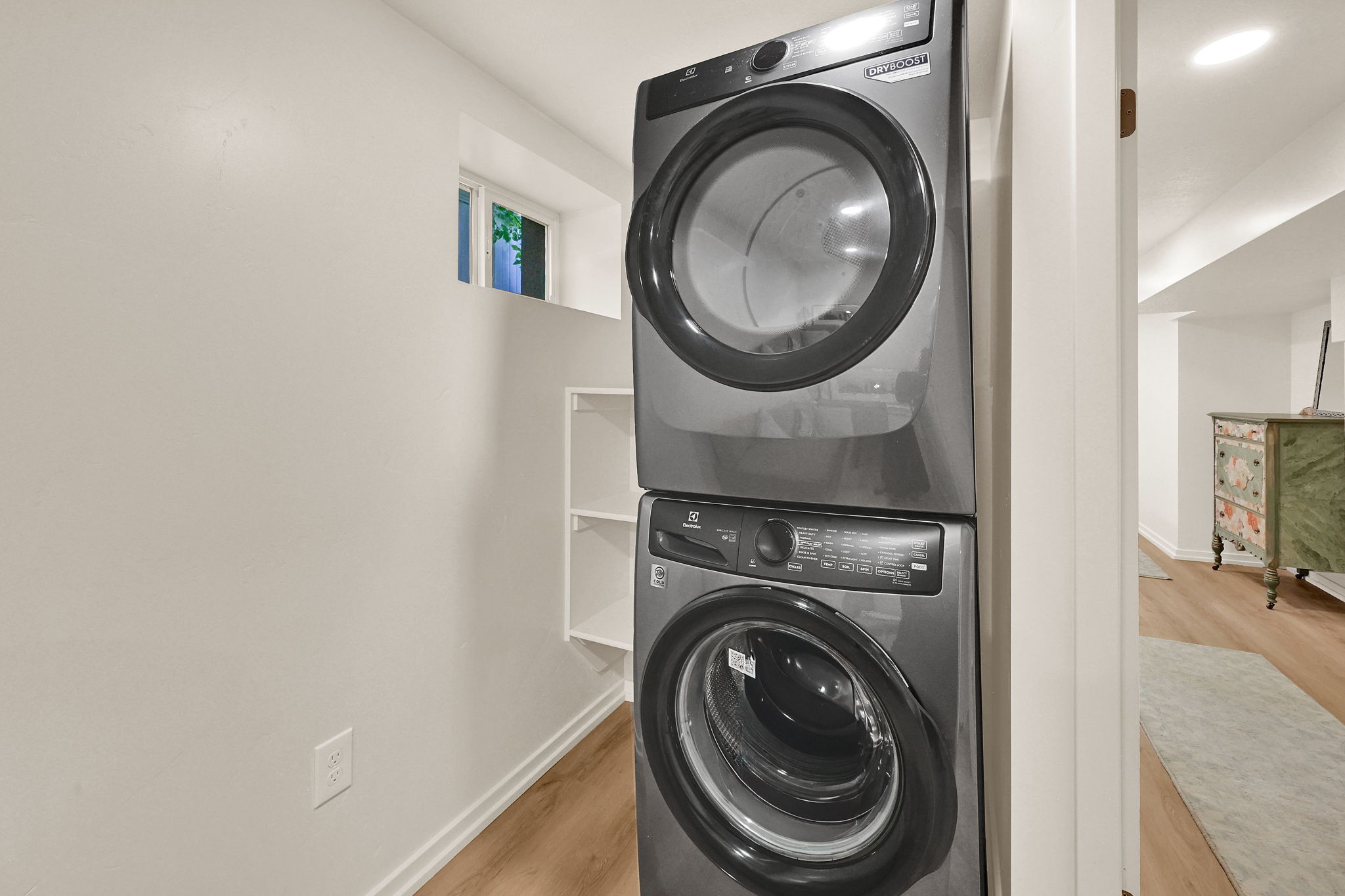 Dedicated laundry area featuring stacked appliances and built-in shelving
