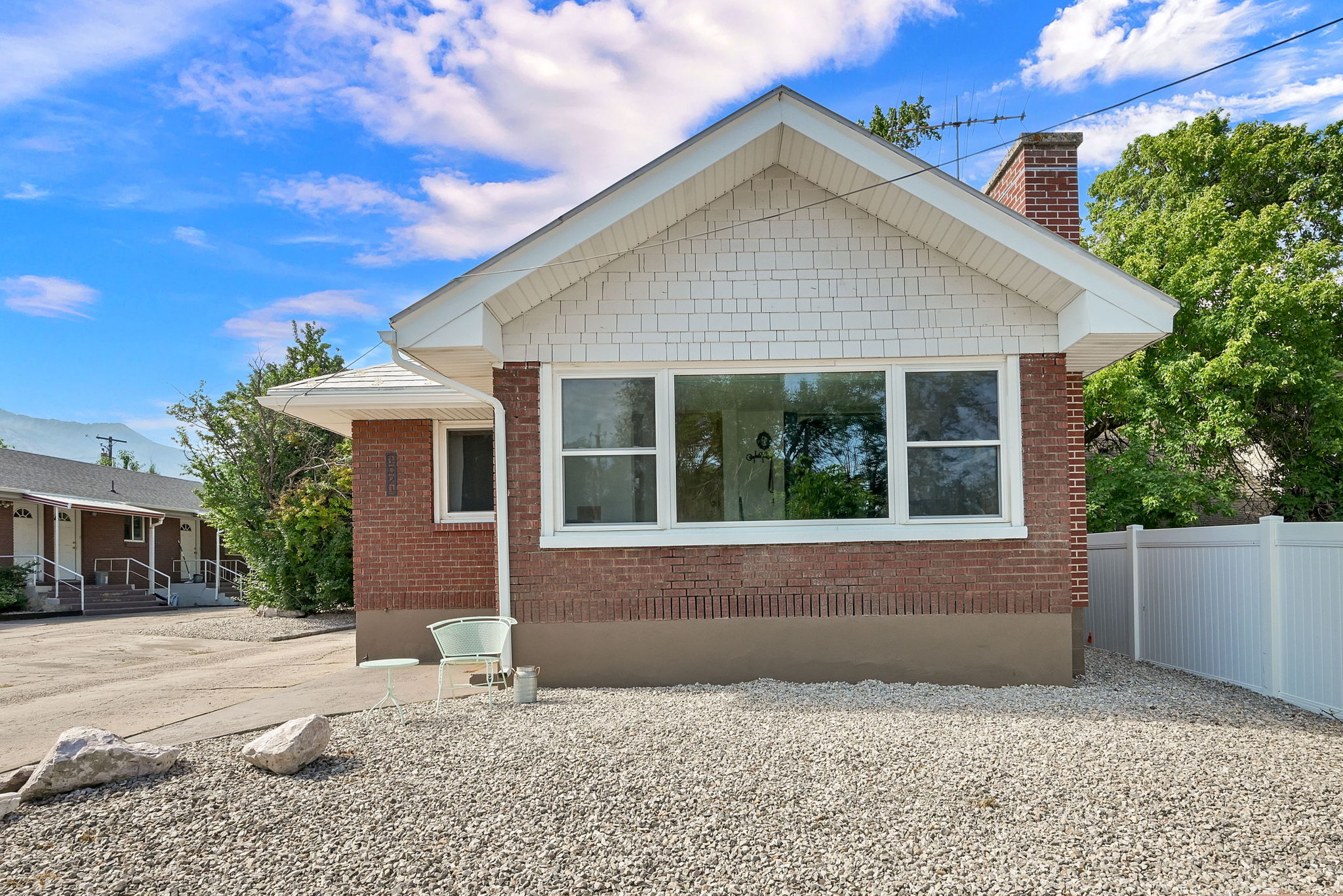 Brick exterior with white shingle siding and a prominent front window