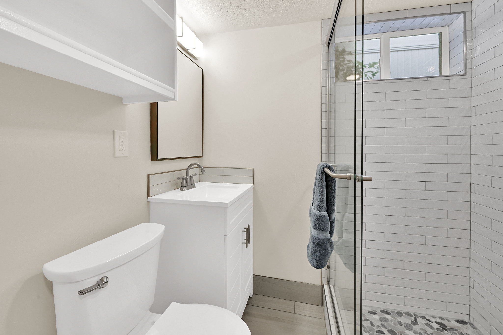 Bathroom featuring a glass-enclosed shower with pebble-finish flooring and white subway tile surround