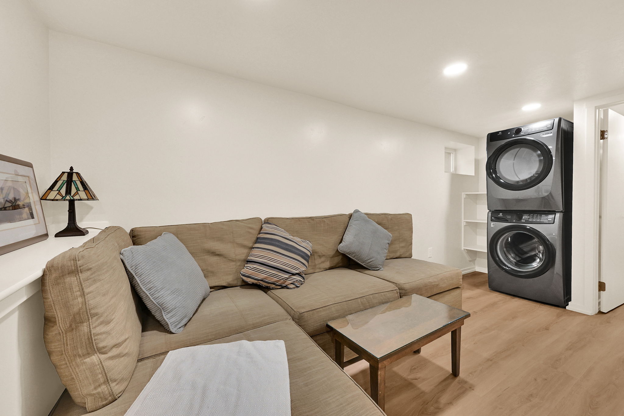 Compact laundry area featuring a stacked washer and dryer, wood-finish flooring, and recessed ceiling lighting