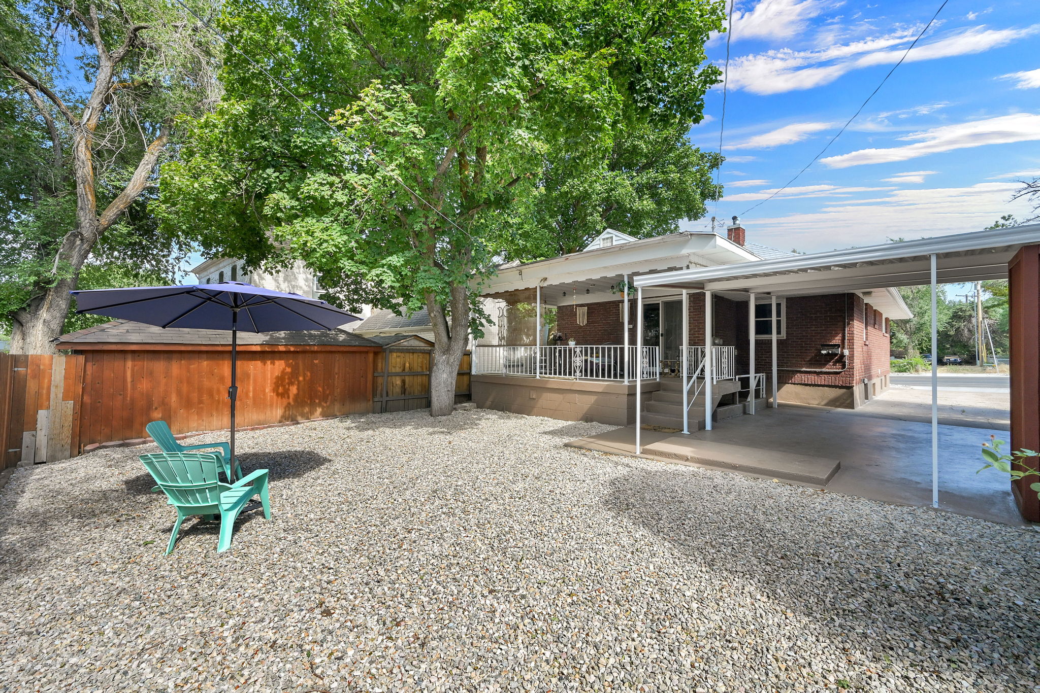 Gravel yard featuring mature trees and a wood privacy fence