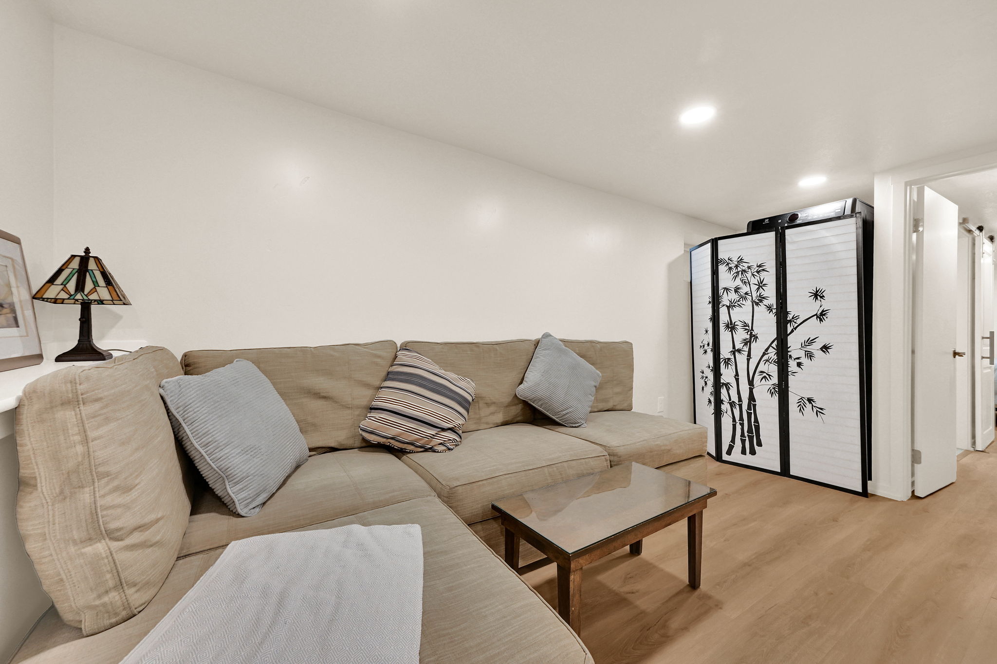 Recessed lighting illuminates this room, featuring wood-finish flooring and a neutral color palette