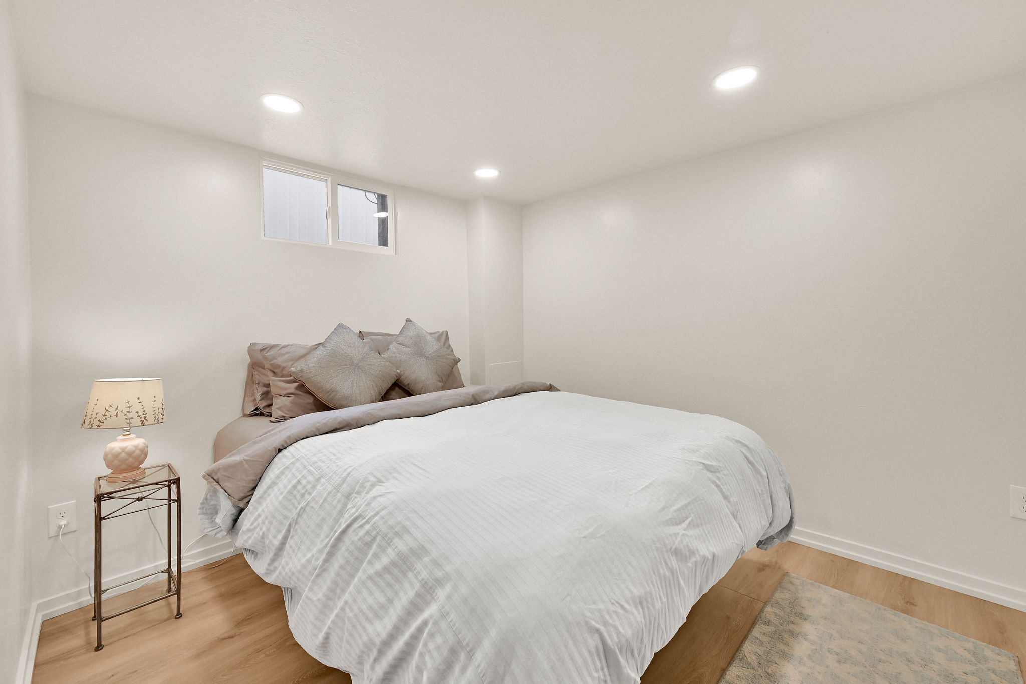 Recessed ceiling lighting, wood-finish flooring, and white baseboards
