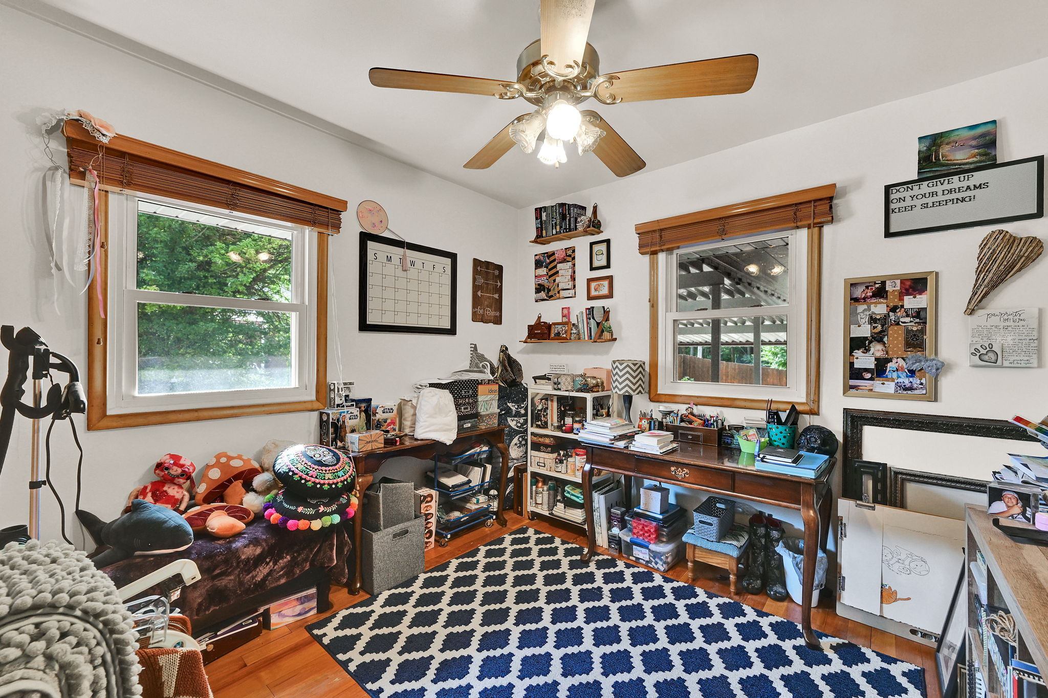Room featuring wood-finish flooring, white walls, and a ceiling fan with light fixture