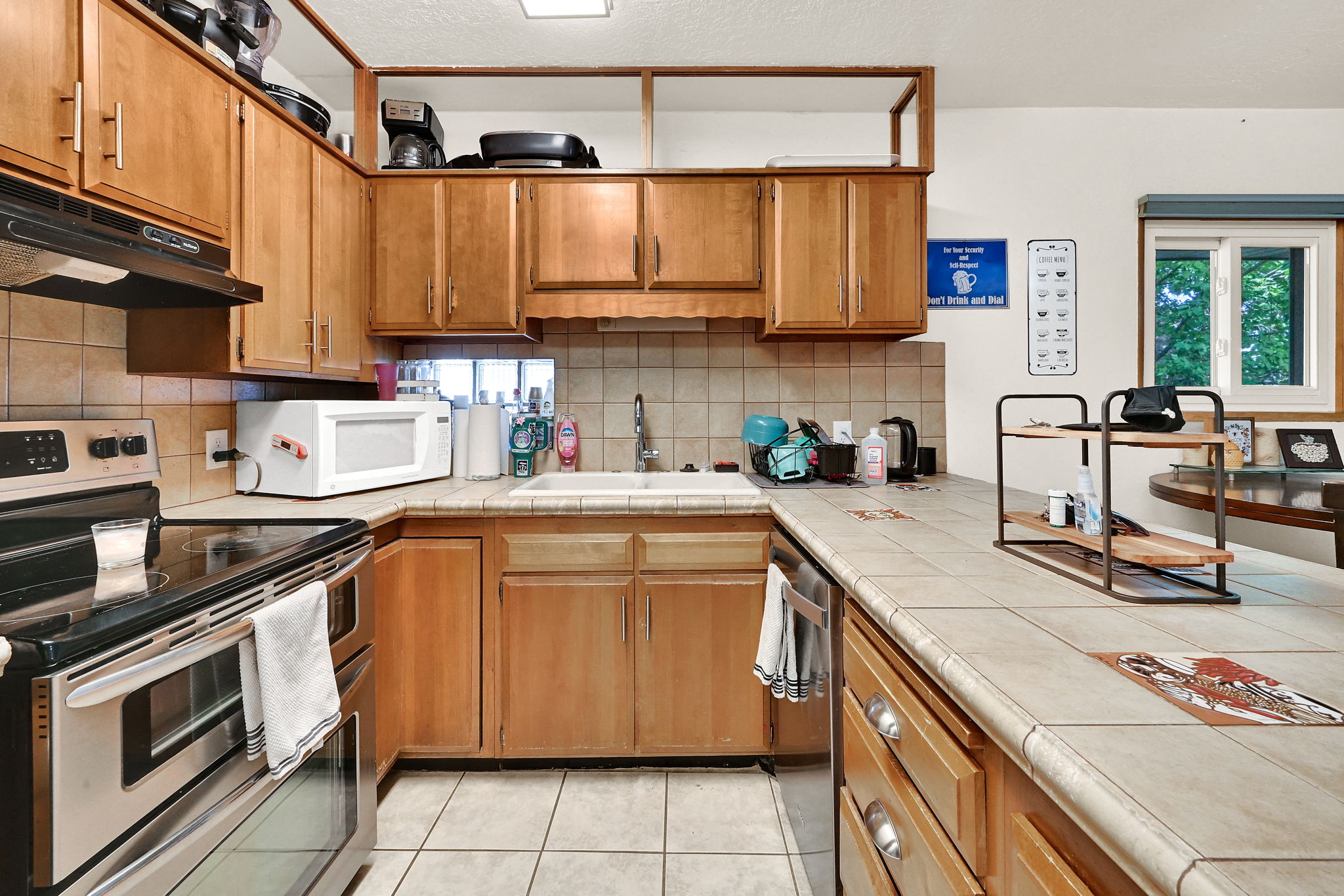 Kitchen featuring wood-finish cabinetry, tile countertops, and a tile backsplash