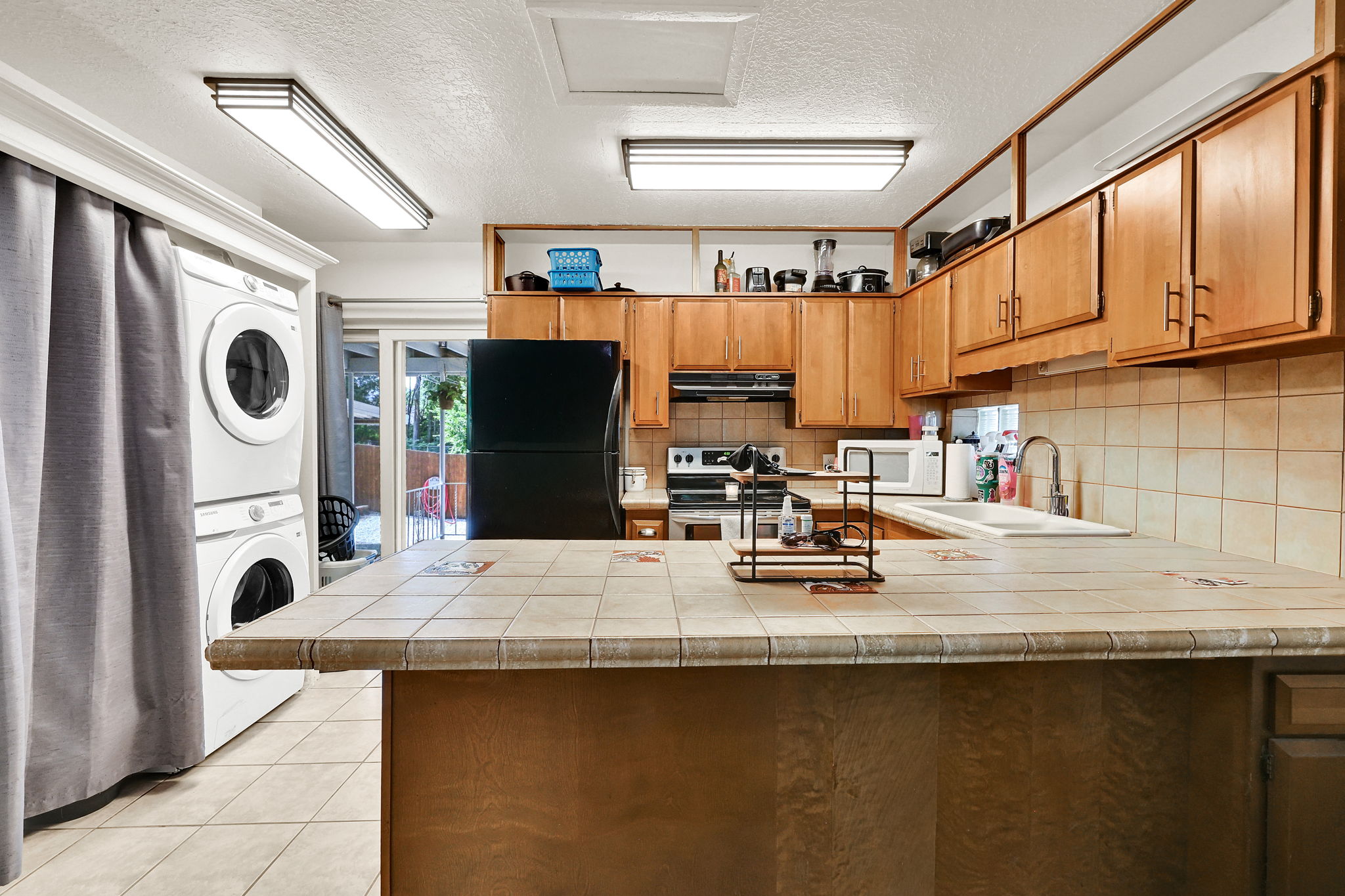 Kitchen featuring wood cabinetry, a tiled backsplash, and an island with a tiled countertop