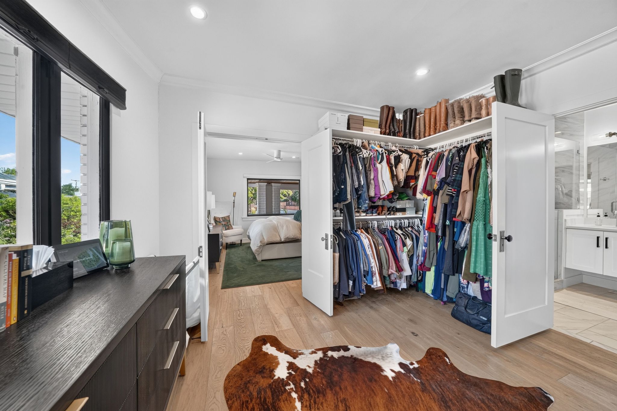 Walk-in closet featuring custom built-ins, light wood-finish flooring, recessed lighting, and crown molding
