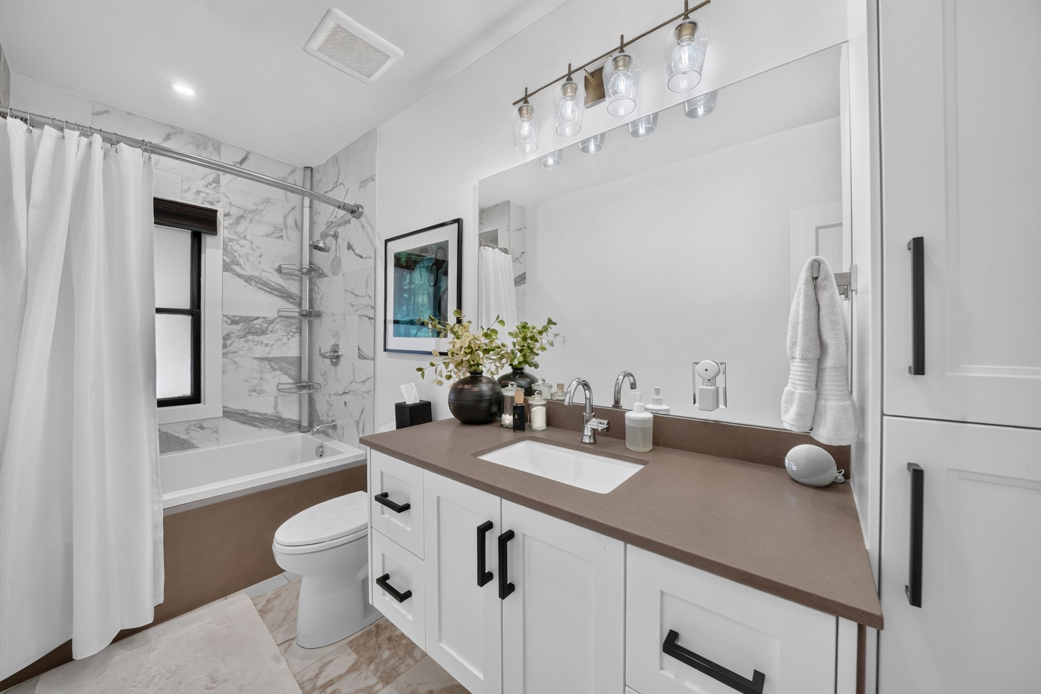 Modern bathroom featuring white cabinetry with matte black hardware, a rectangular undermount sink, and a solid surface countertop