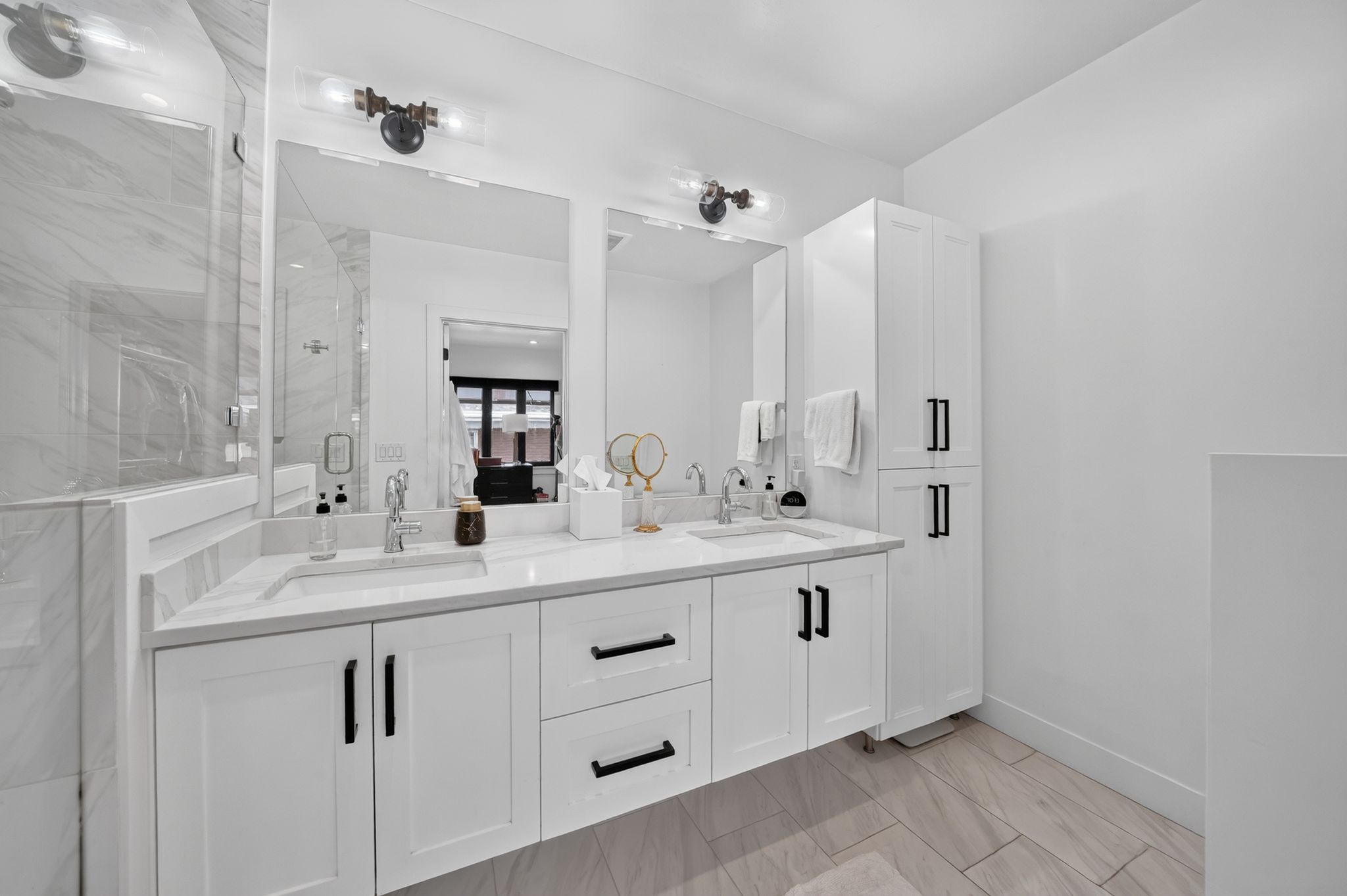 Contemporary bathroom featuring a double vanity with white cabinetry, a light-toned countertop, and dual wall-mounted light fixtures