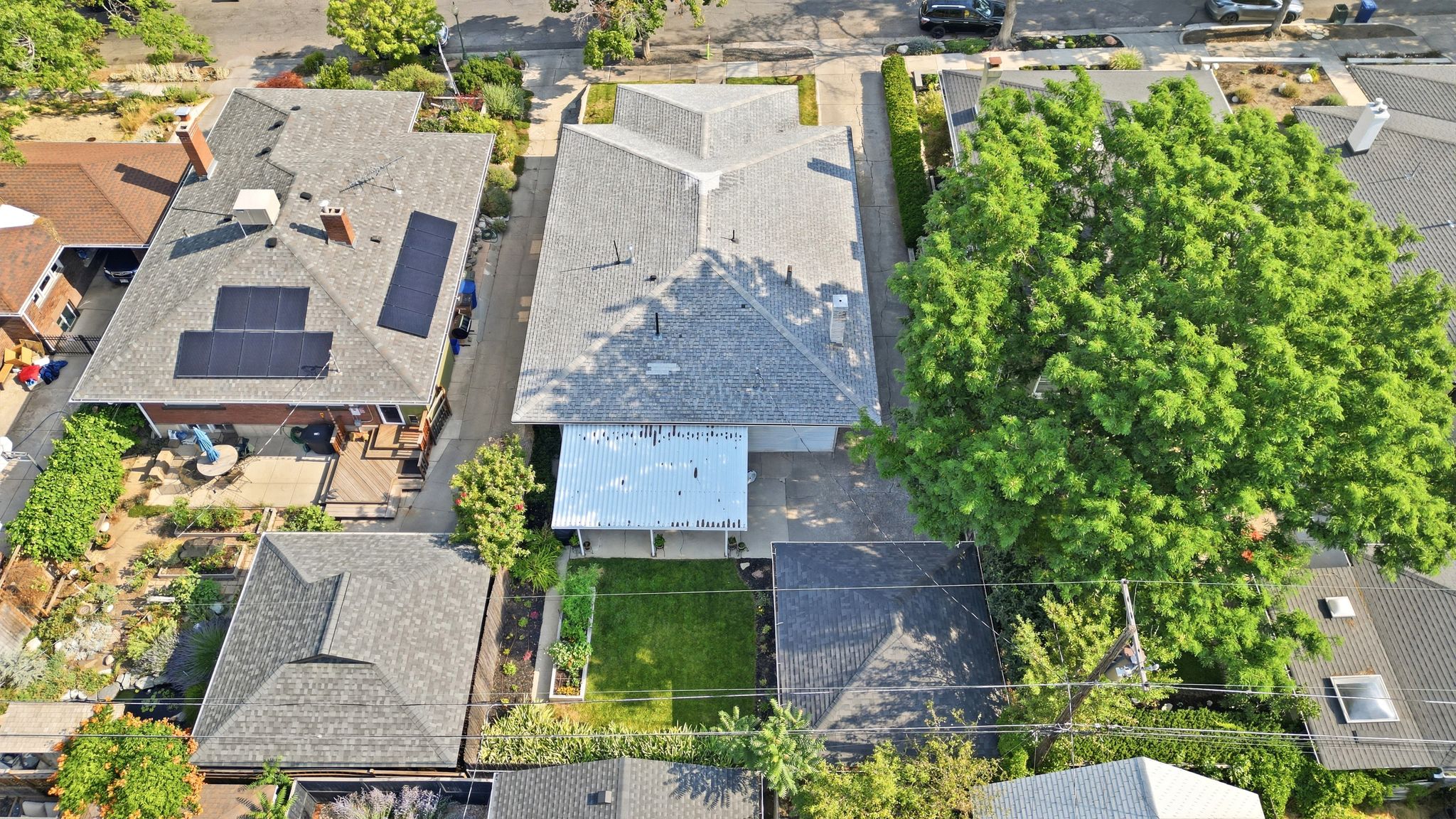 Aerial perspective showcasing multiple properties, featuring a main residence with a gray shingle roof and a separate structure with a shingle roof