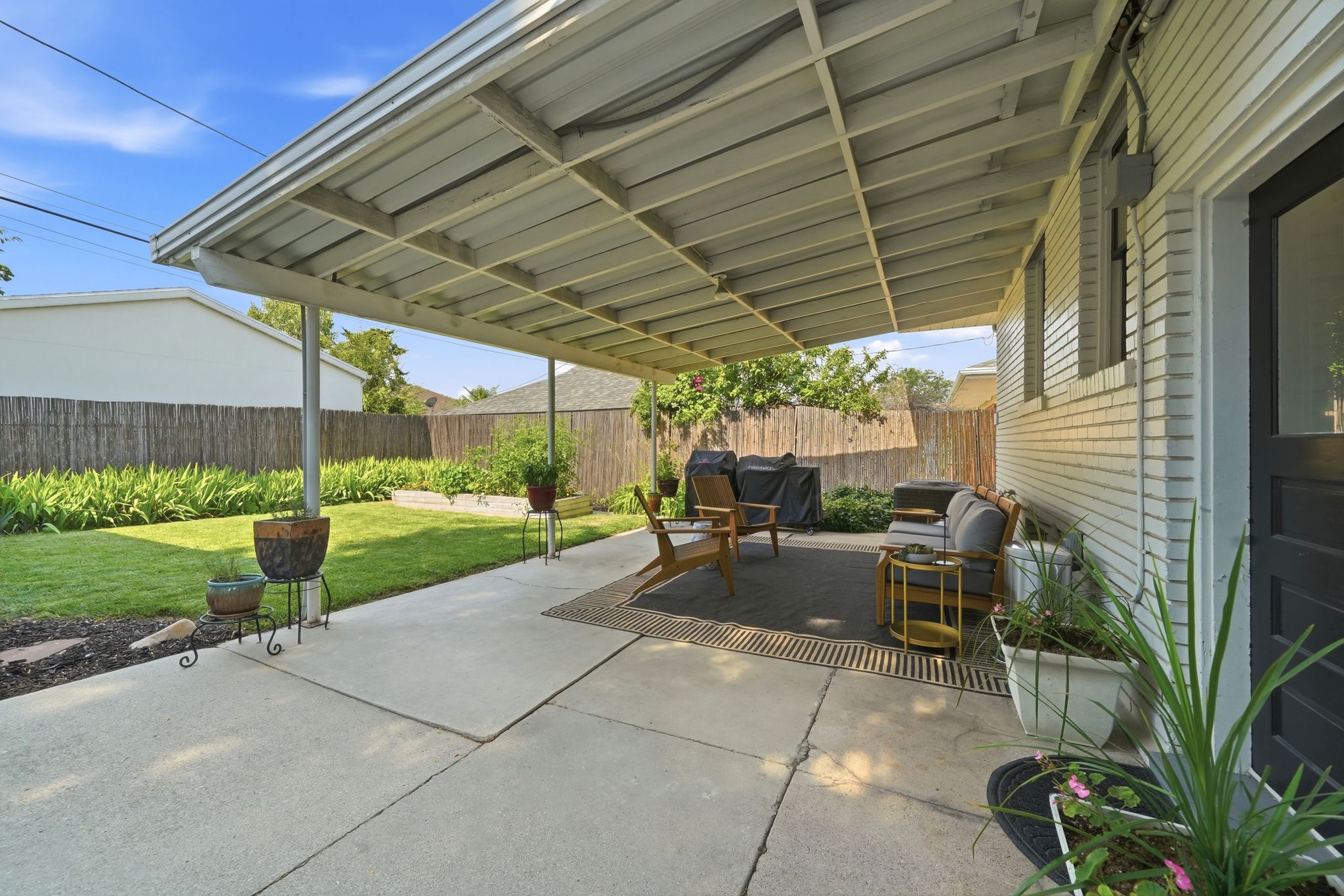 Covered patio area featuring a concrete surface and slatted overhead structure