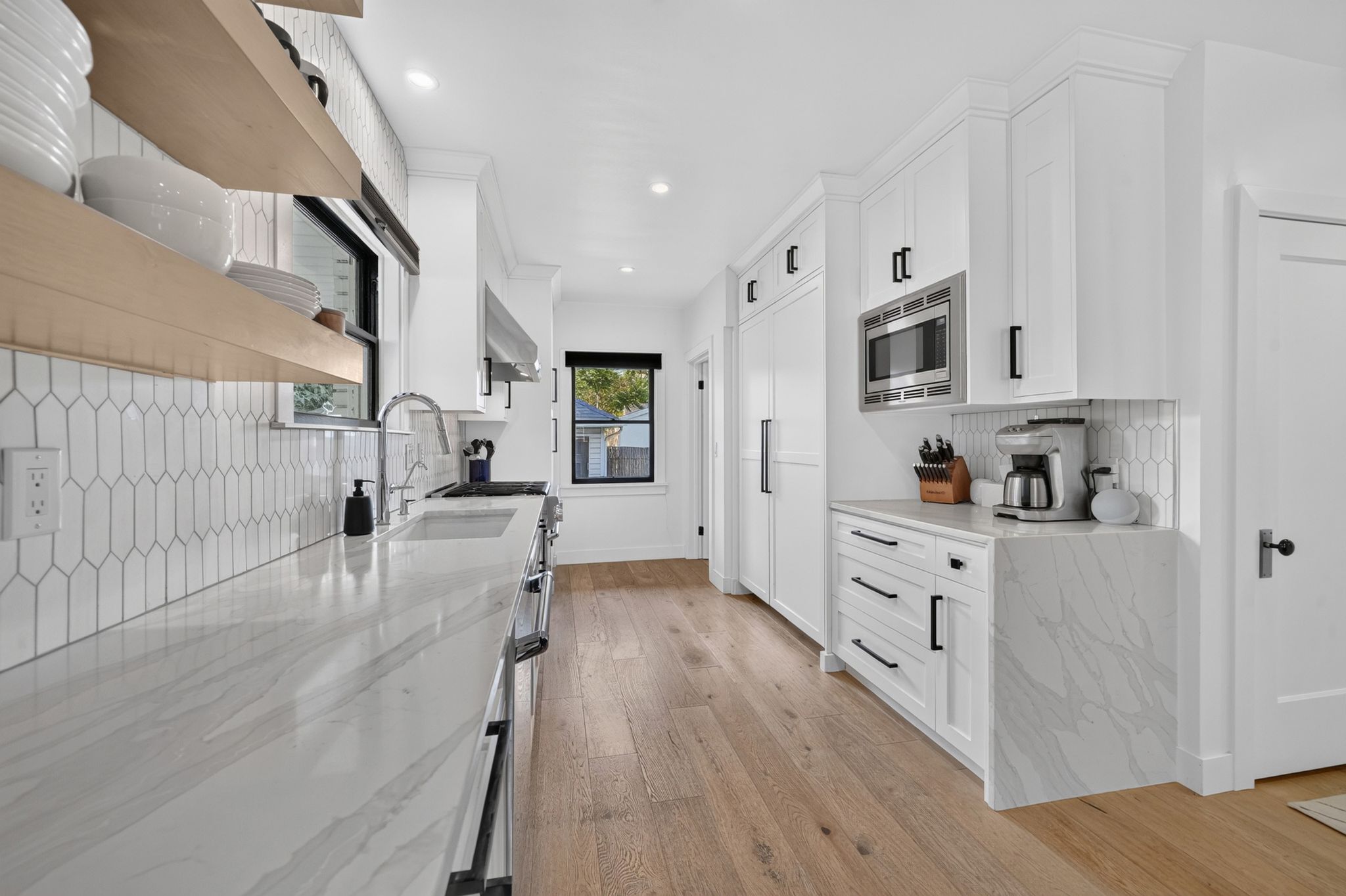 Modern kitchen featuring white cabinetry, light wood-finish flooring, and light-toned countertops with subtle veining