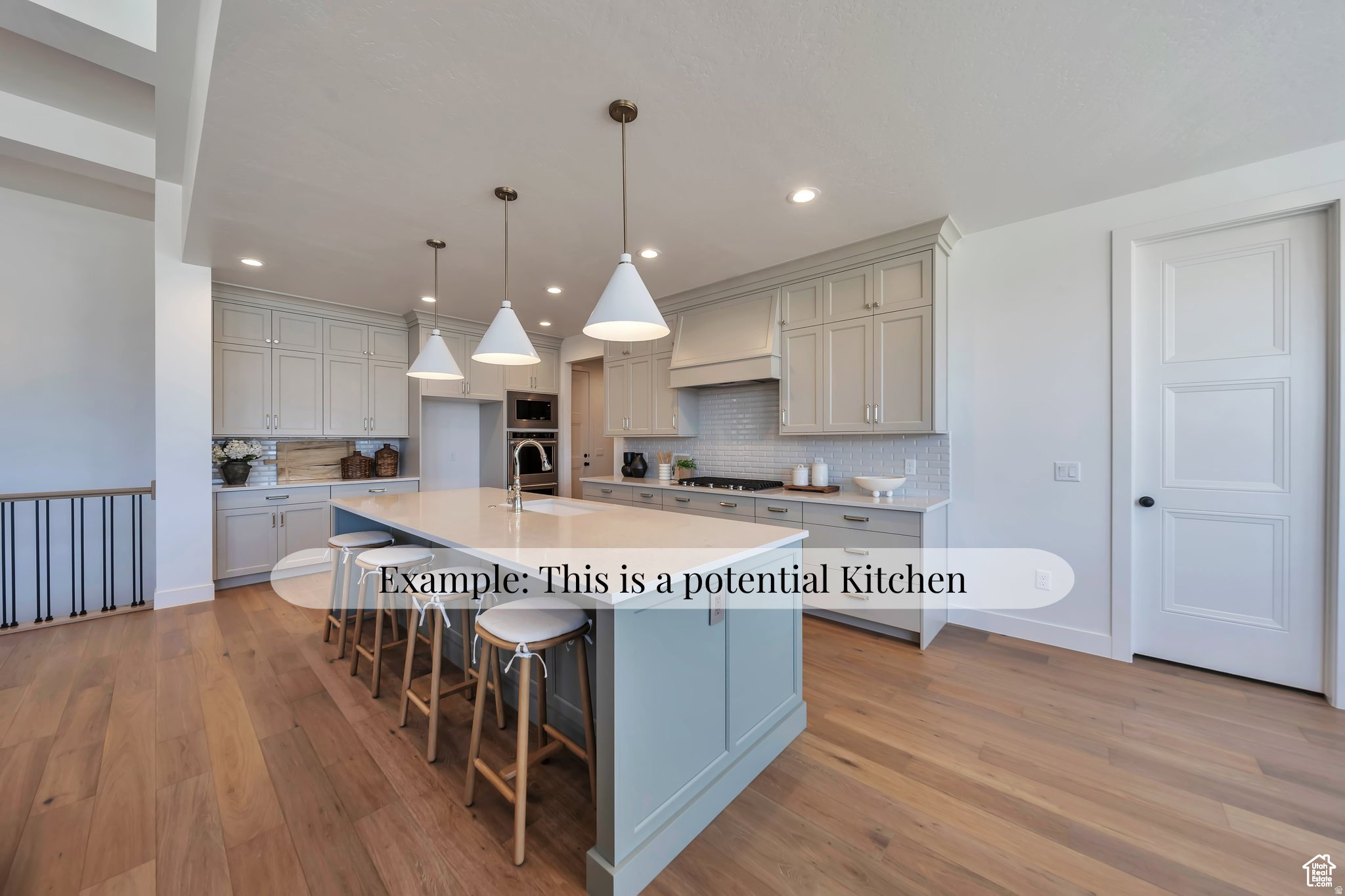 Spacious kitchen featuring a large central island with seating, pendant lighting, light wood-finish flooring, light gray cabinetry, and a subway tile backsplash