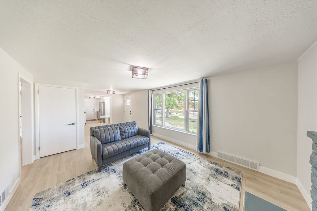 Living space featuring light wood-finish flooring, white baseboards, and a large multi-pane window