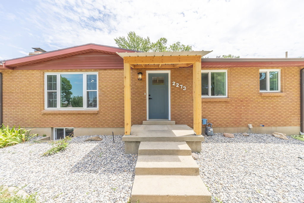 Brick exterior with a covered entry featuring a light wood pergola