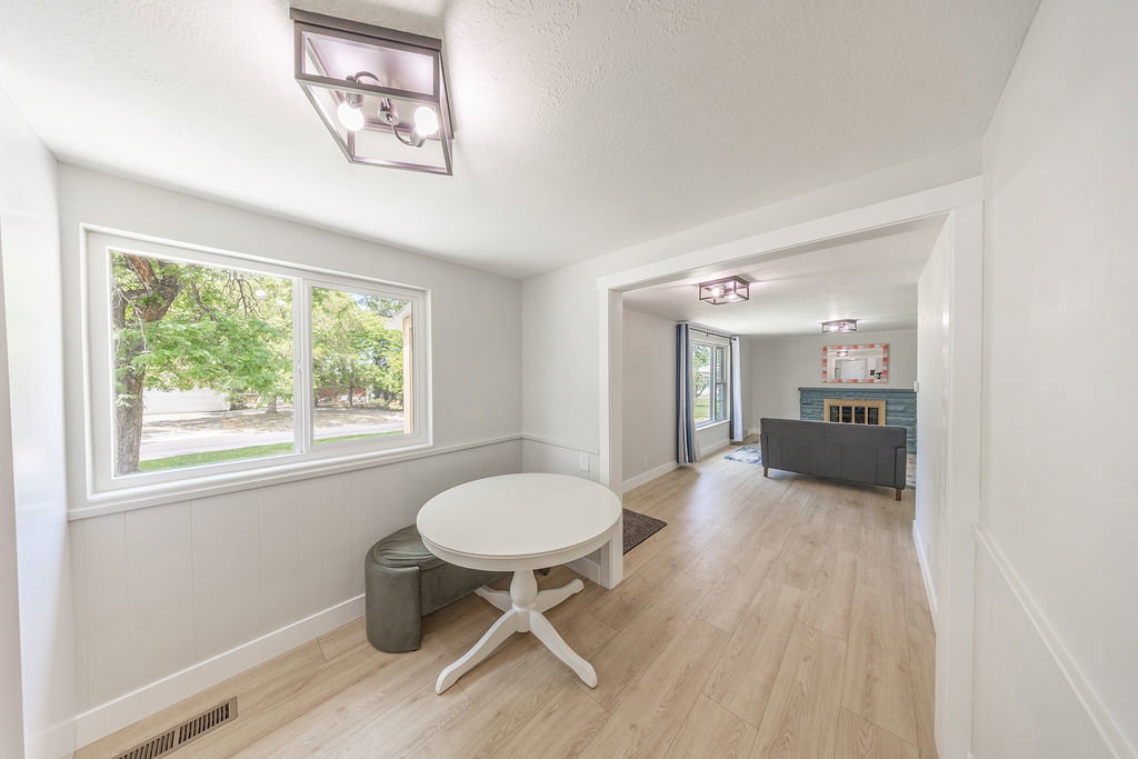 Bright interior featuring light wood-finish flooring, white paneled wainscoting, and a large window