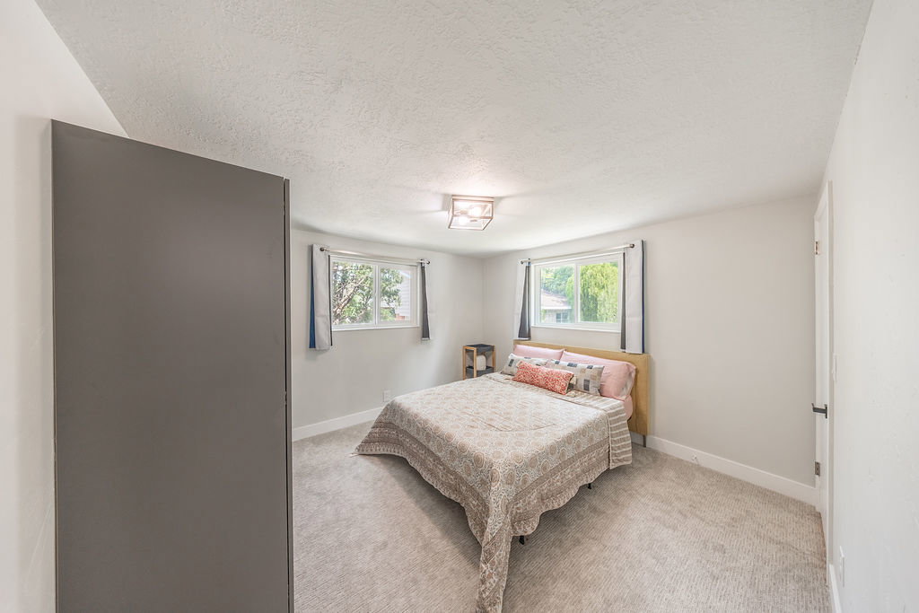 Carpeted room featuring two windows, neutral wall tones, and a ceiling-mounted light fixture