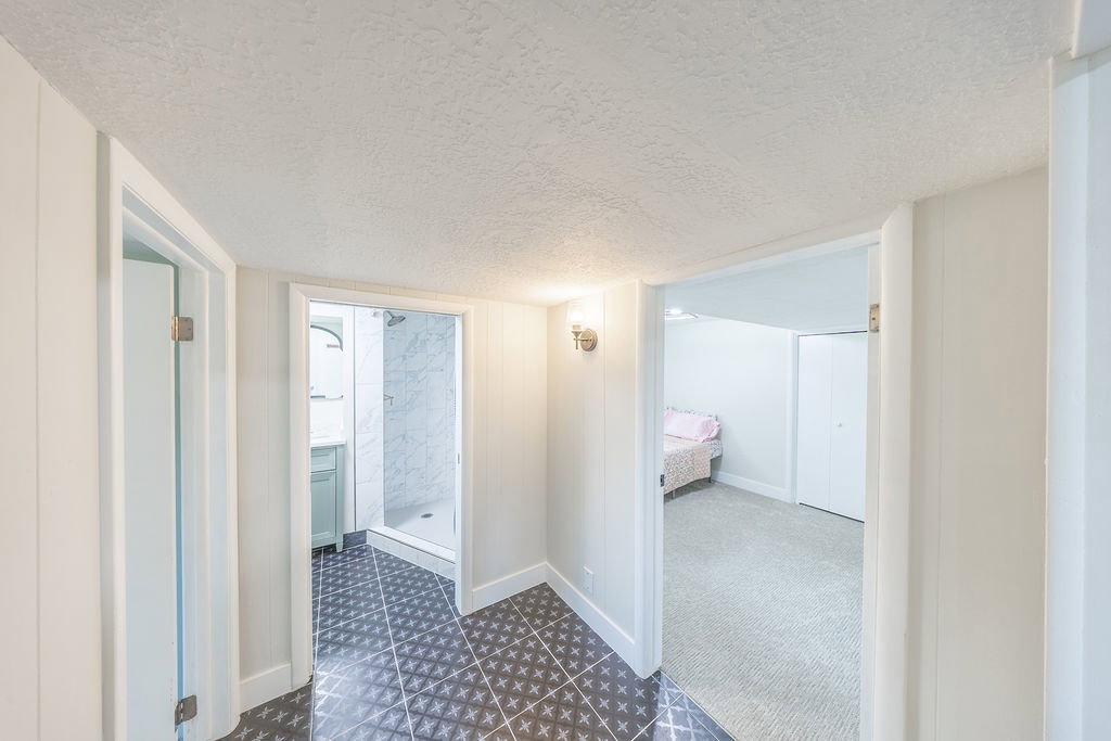 Hallway featuring a decorative tile floor, white wall paneling, and recessed lighting