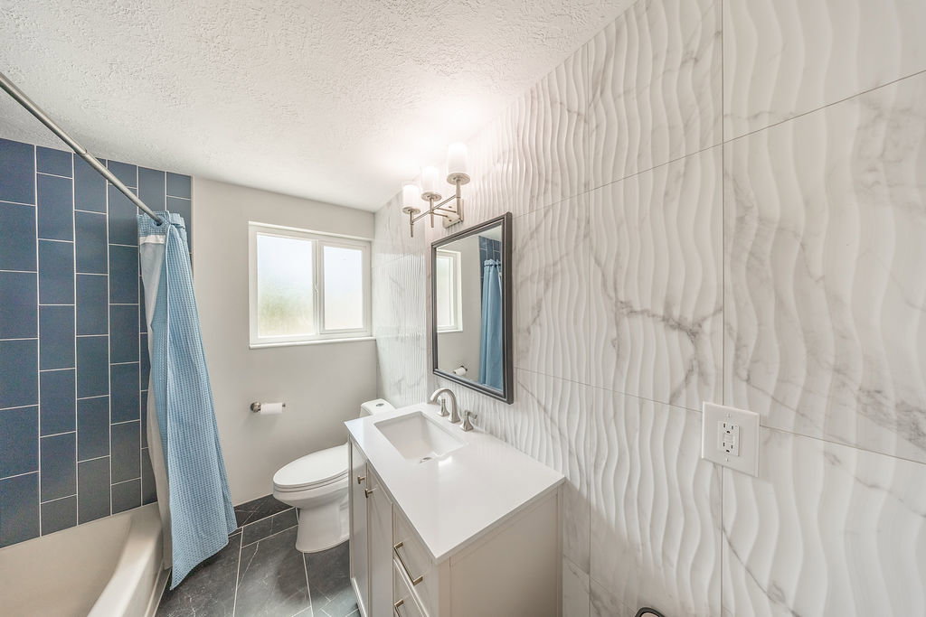 Bathroom featuring a white vanity with an integrated sink, polished chrome faucet, and a rectangular framed mirror