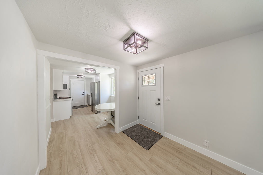 Entryway featuring a white paneled door with decorative glass, wood-finish flooring, and a modern flush-mount ceiling light