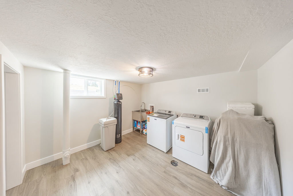 Utility room featuring wood-finish flooring, white walls, and a ceiling-mounted light fixture