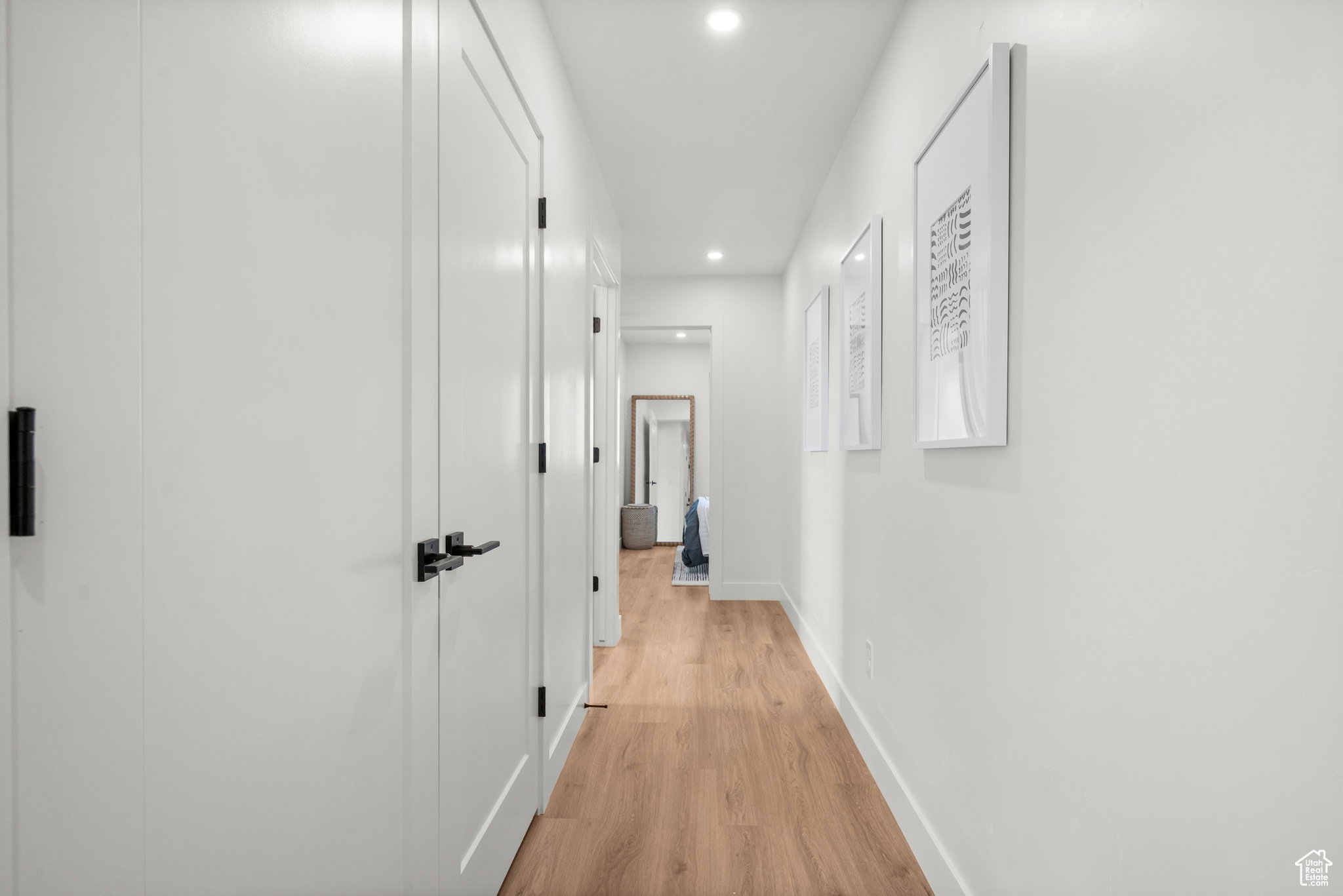 Hallway featuring light wood-finish flooring, recessed lighting, and white walls