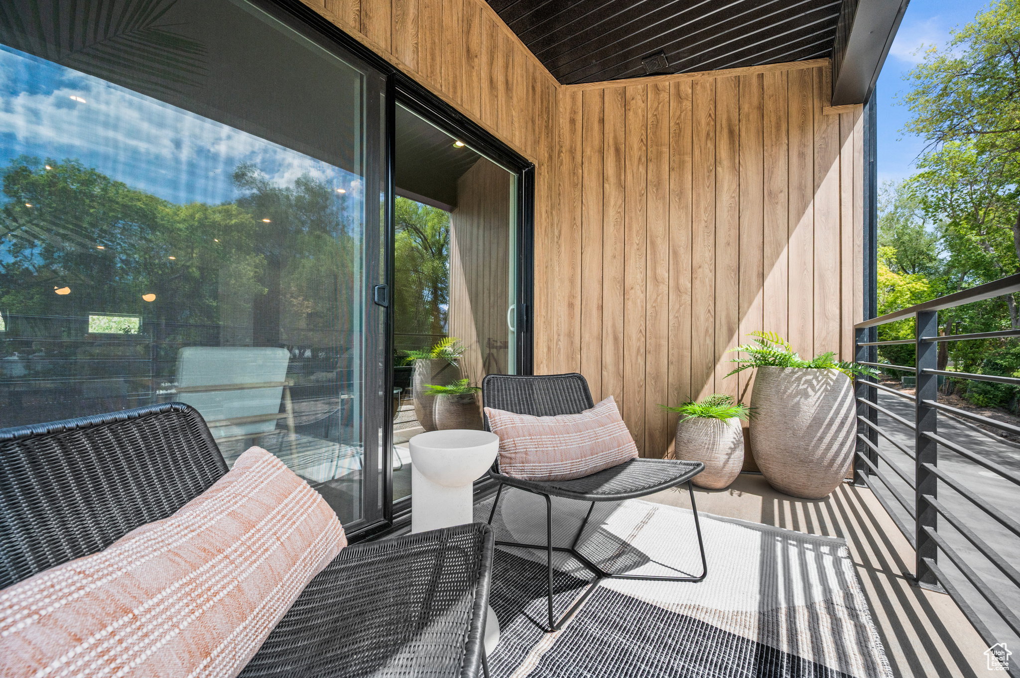 Balcony featuring wood-finish paneling, black metal railing, and a large sliding glass door