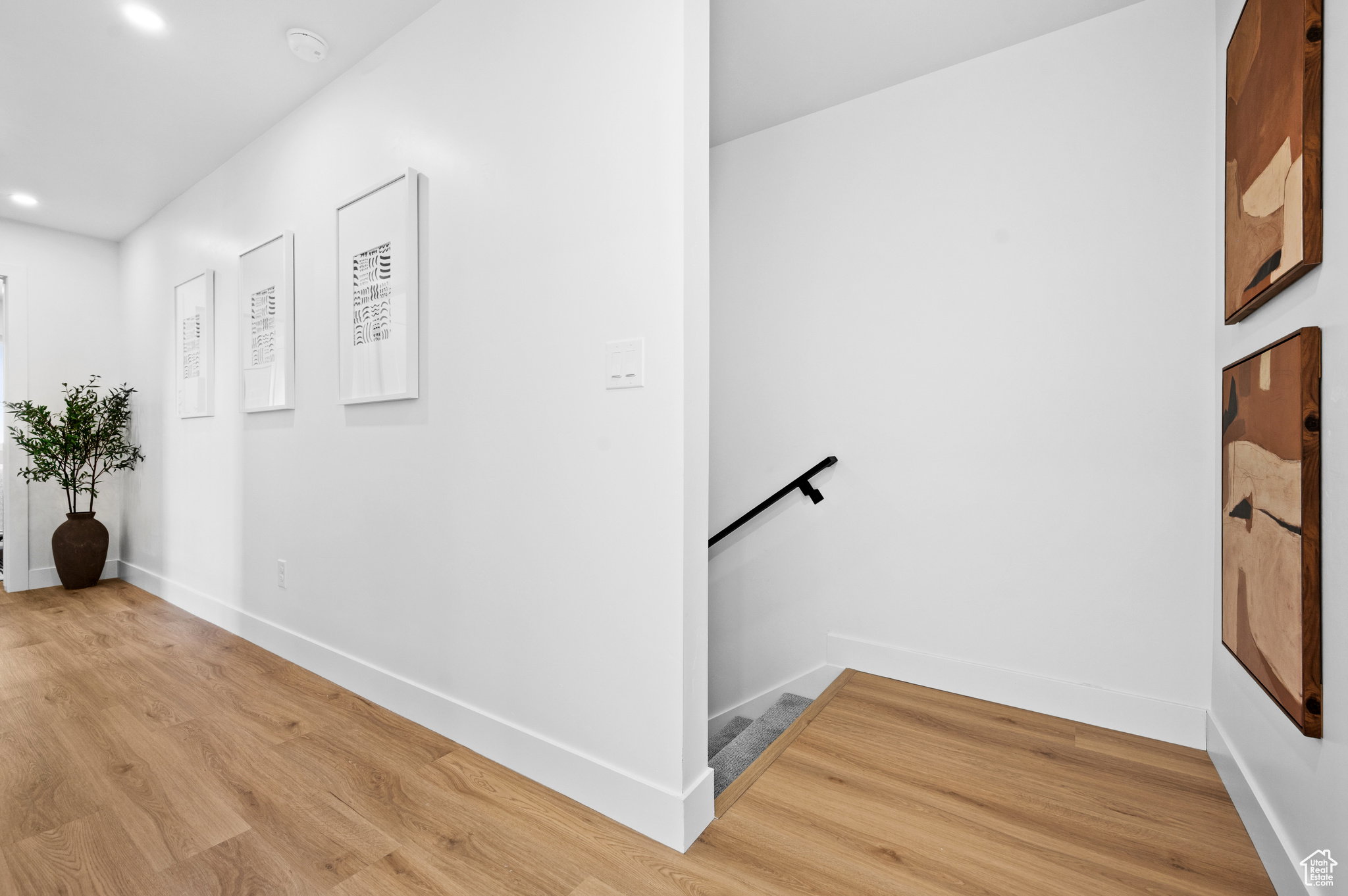 Hallway featuring wood-finish flooring, recessed lighting, and crisp white walls