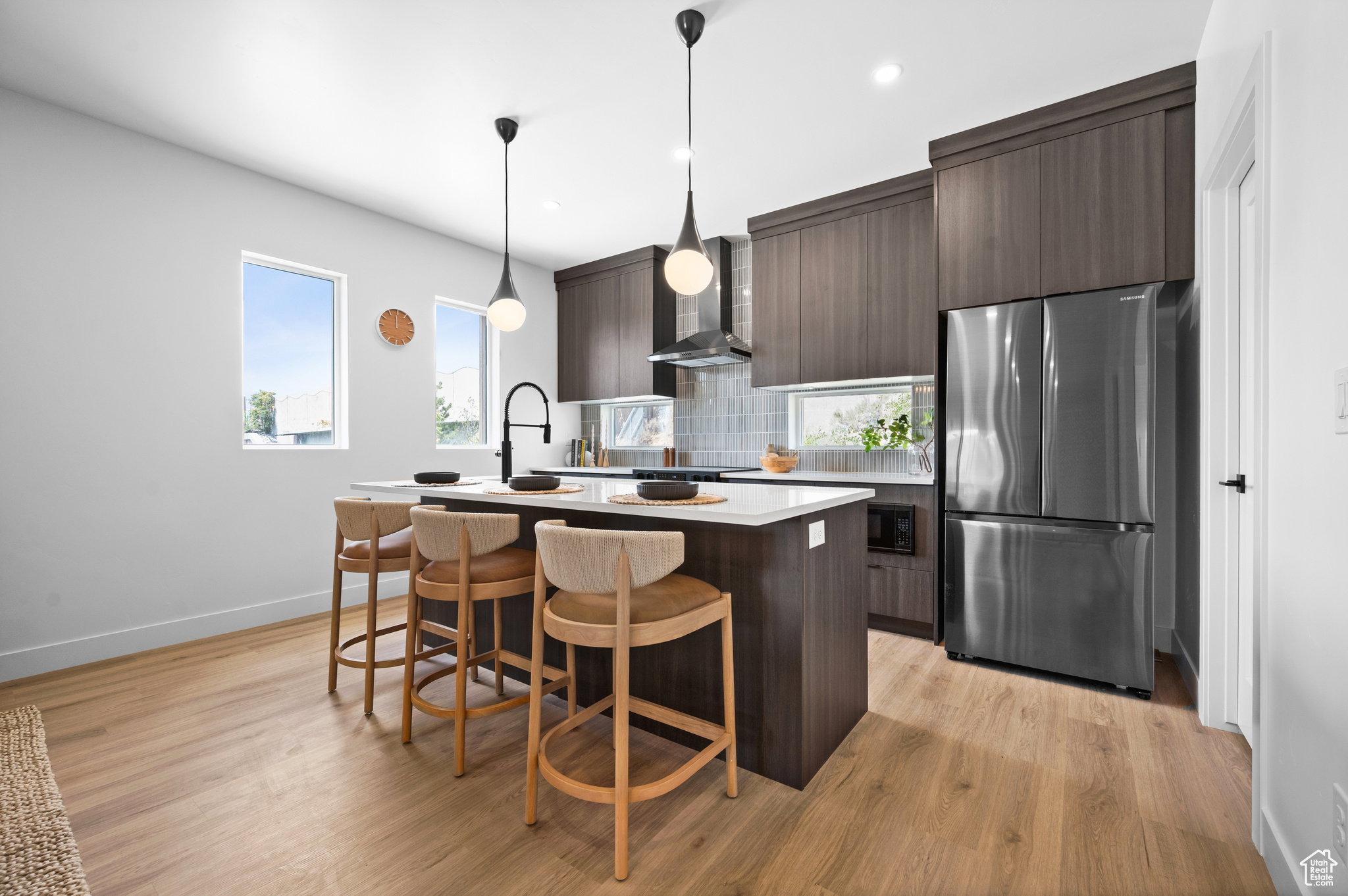 Kitchen featuring an island with seating, dark wood-finish cabinetry, a stainless steel refrigerator, and wood-finish flooring