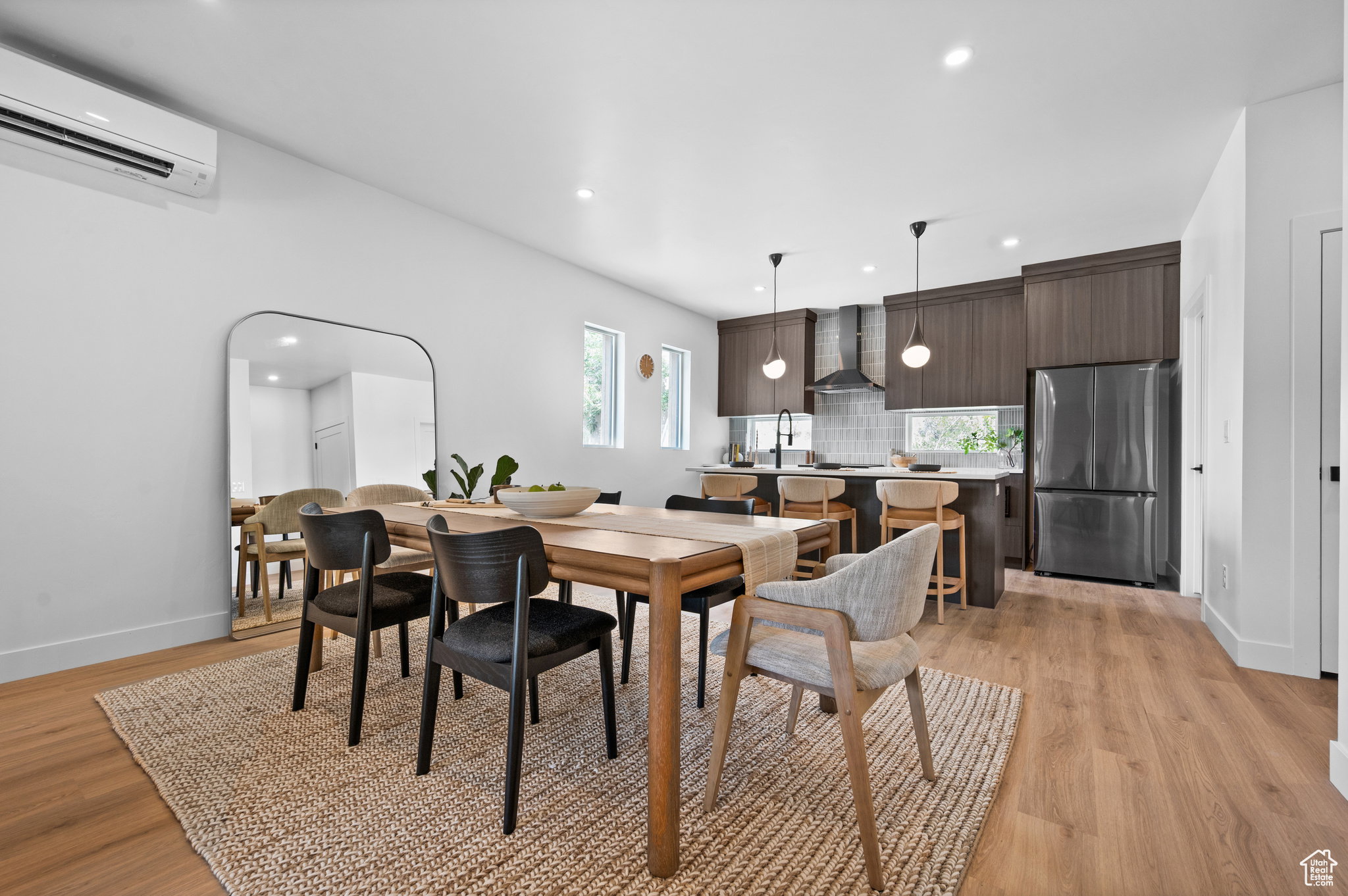 Contemporary open-concept dining area and kitchen featuring wood-finish flooring, recessed lighting, and a ductless mini-split system