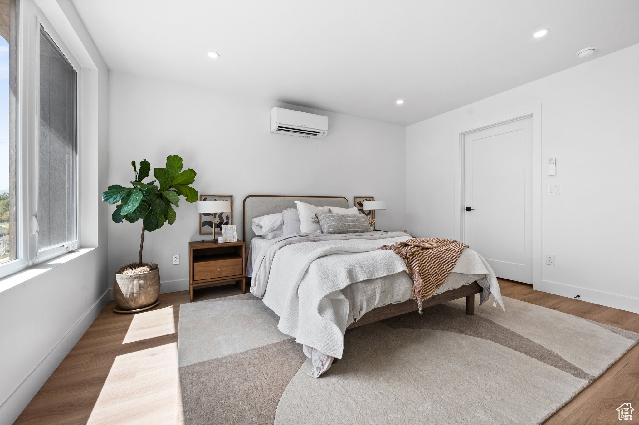 Bedroom featuring wood-finish flooring, recessed lighting, and a window with white trim