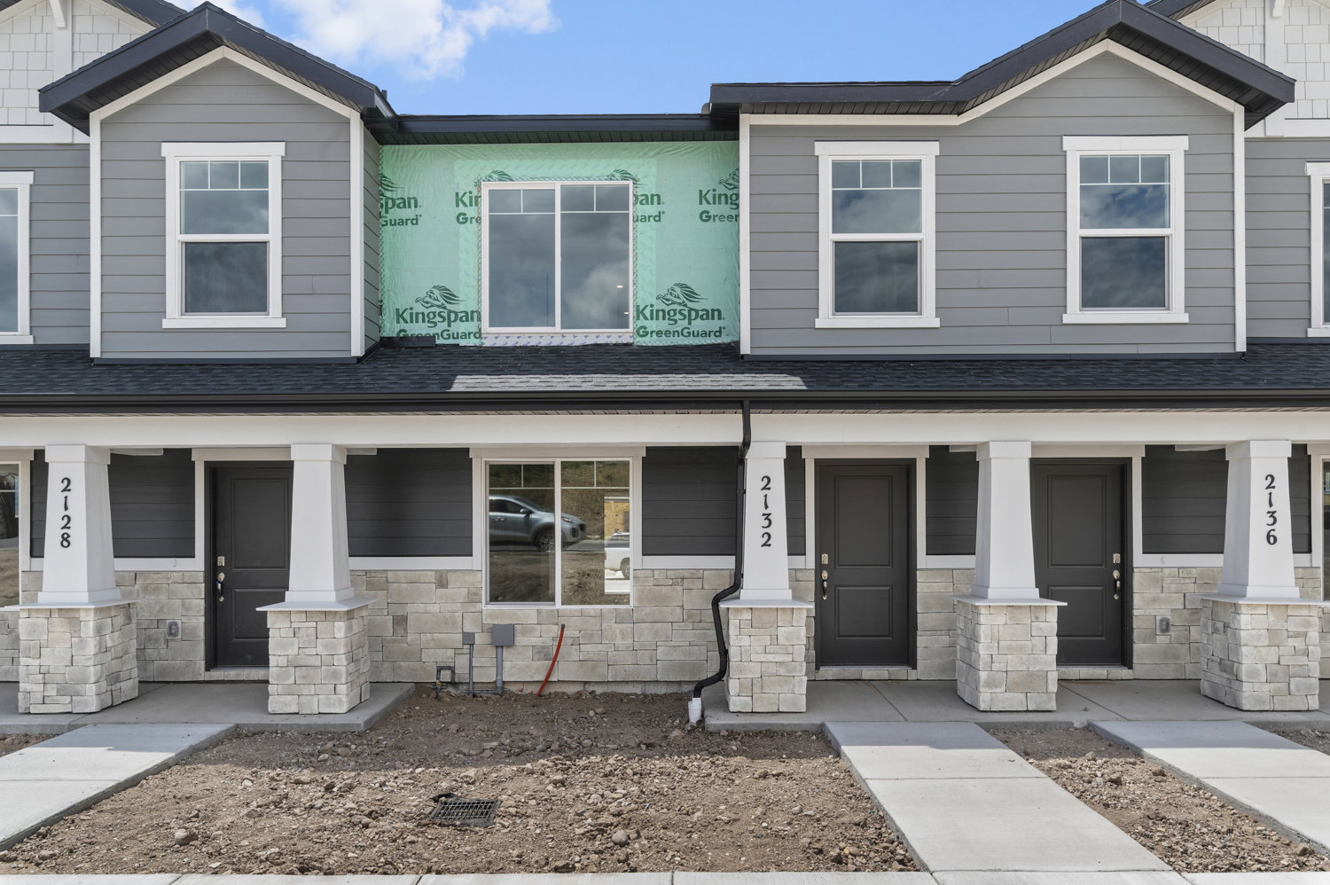 Modern townhouse facade featuring horizontal siding and stone veneer accents