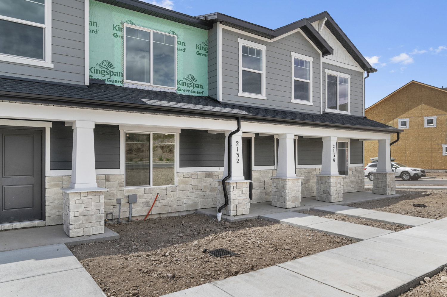 Contemporary townhome exterior featuring gray siding and stone veneer accents