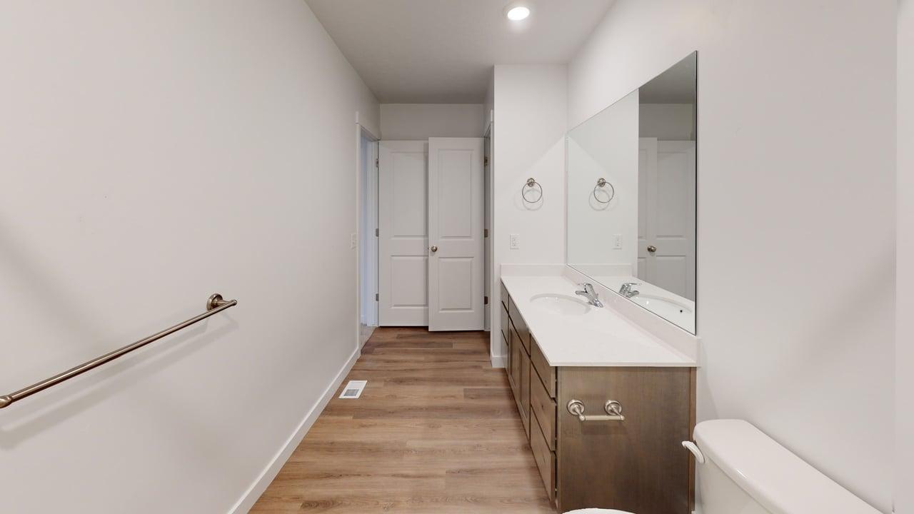 Bathroom featuring a dual vanity with a white countertop, two undermount sinks, and contemporary wood-finish cabinetry